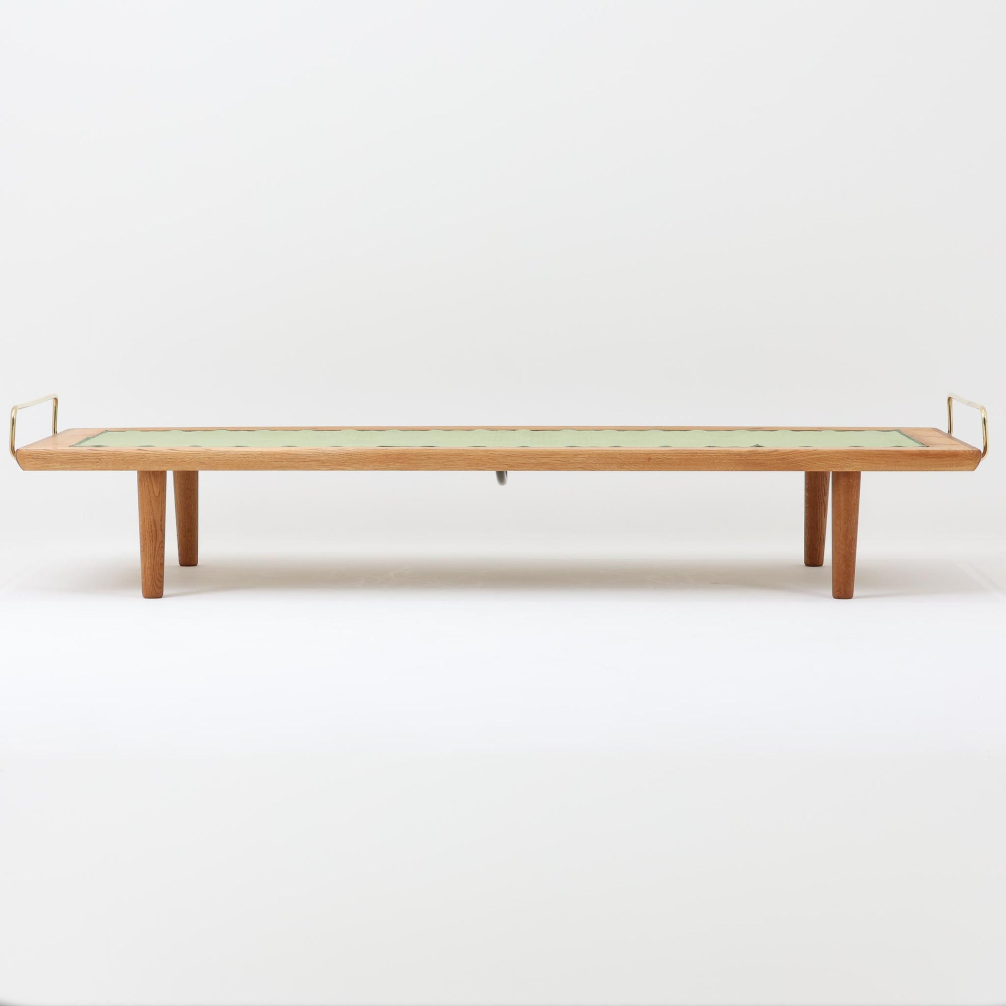 Hans J. Wegner（ハンス・J・ウェグナー）がGetama社のために手掛けたGE19 ベンチソファは、端正なプロポーションと素材使いが際立つ北欧ビンテージの名作です。フレームにはオーク材を用い、細身で安定感のある脚部と、両端に配されたメタルパーツが軽やかなアクセントとなっています。マットレスやクッションを合わせることで、ベンチとしてもベッドとしても幅広く活用可能です。経年により深みを増した木肌と、当時の職人技が感じられる構造が、空間に静かな存在感と上質な佇まいをもたらします。