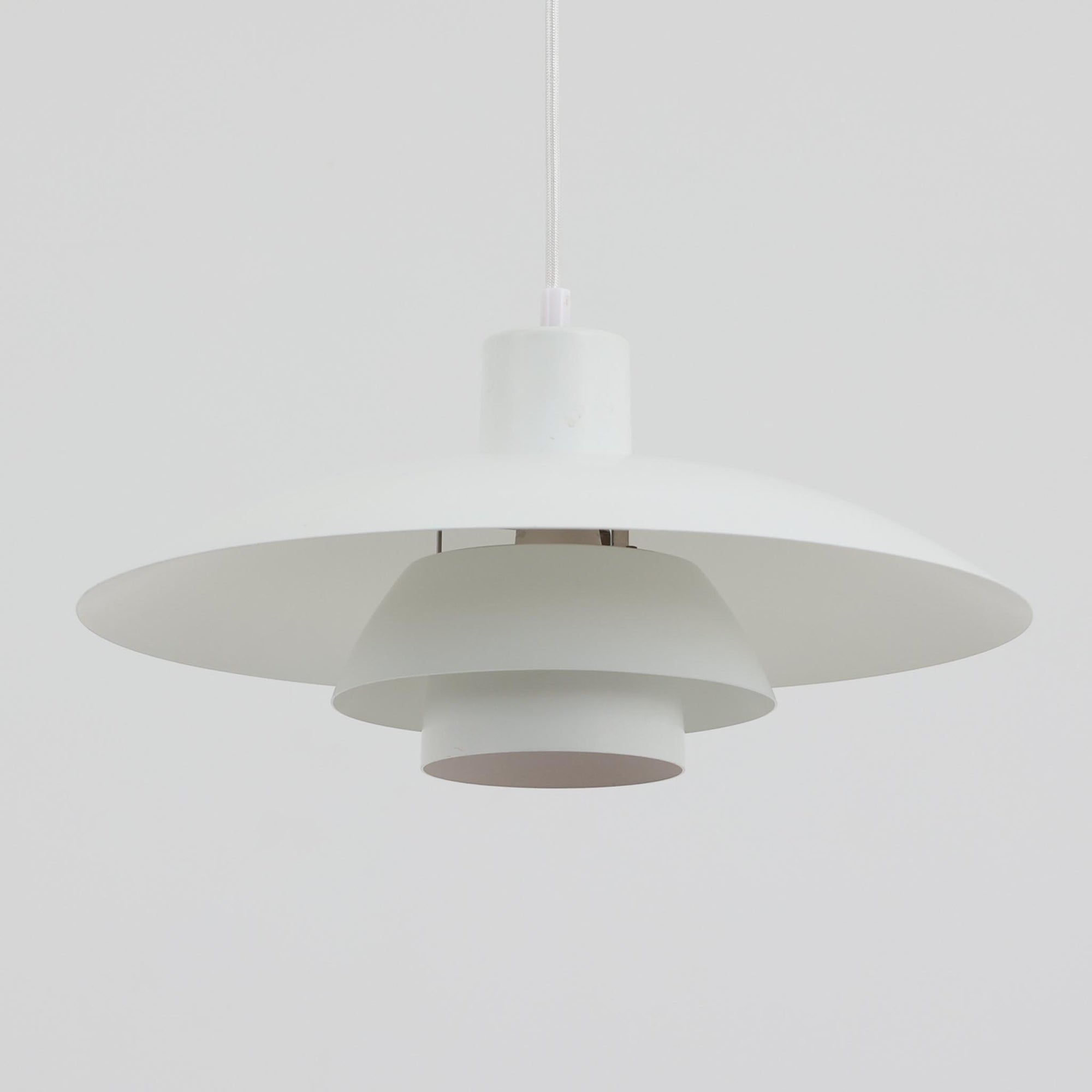 北欧より買い付けたLouis Poulsen社製「PH4」は、Poul Henningsenによる名作照明で、直径40cmの程よいサイズとアルミの軽やかな質感が魅力です。PH5と並ぶ人気を誇り、3枚シェード構造が光を柔らかく拡散し落ち着いた空間を演出します。経年の風合いも楽しめ、ダイニングやリビング、書斎や寝室まで幅広く活躍するビンテージ品です。