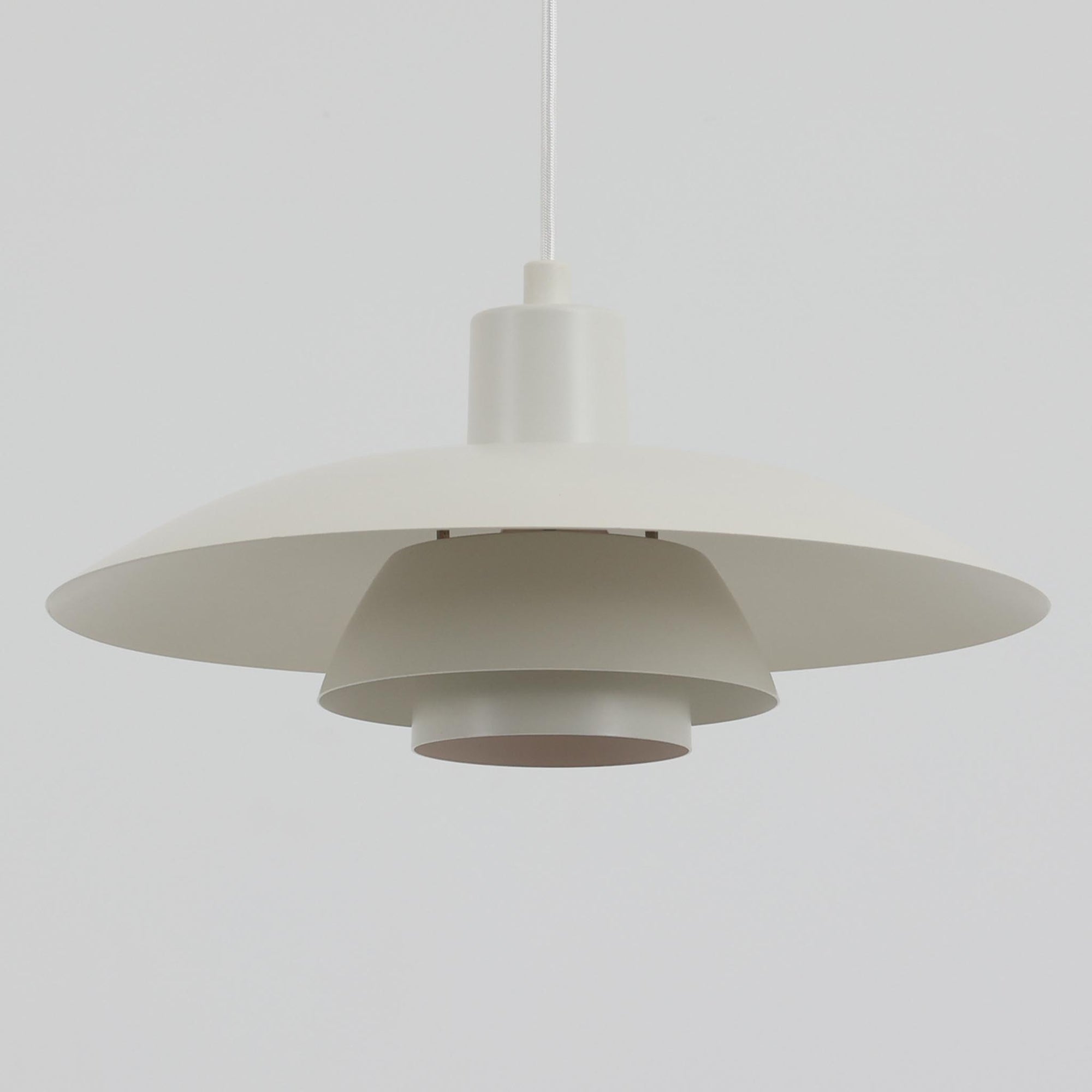 北欧より買い付けたLouis Poulsen社製「PH4」は、Poul Henningsenによる名作照明で、直径40cmの程よいサイズとアルミの軽やかな質感が魅力です。PH5と並ぶ人気を誇り、3枚シェード構造が光を柔らかく拡散し落ち着いた空間を演出します。経年の風合いも楽しめ、ダイニングやリビング、書斎や寝室まで幅広く活躍するビンテージ品です。