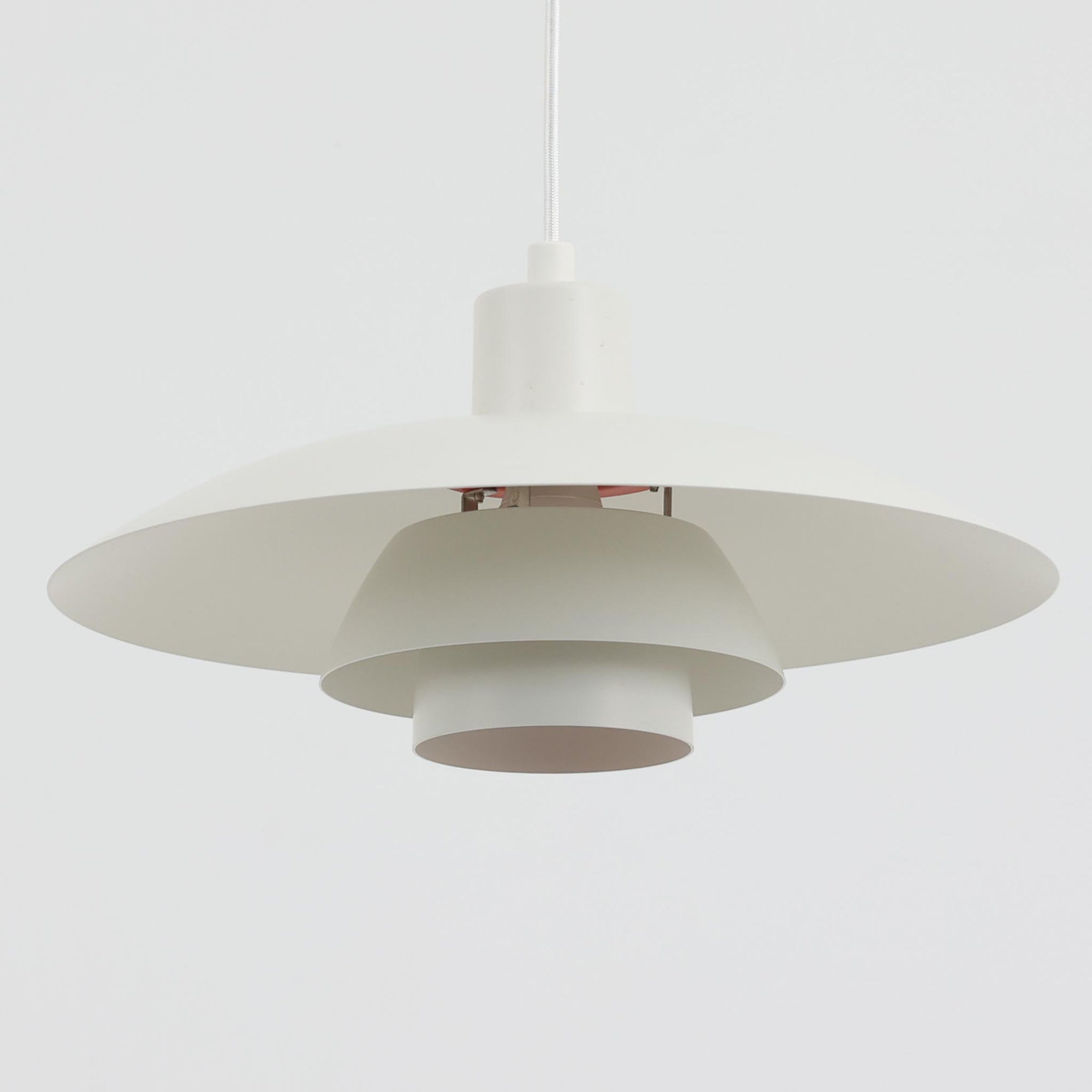 北欧より買い付けたLouis Poulsen社製「PH4」は、Poul Henningsenによる名作照明で、直径40cmの程よいサイズとアルミの軽やかな質感が魅力です。PH5と並ぶ人気を誇り、3枚シェード構造が光を柔らかく拡散し落ち着いた空間を演出します。経年の風合いも楽しめ、ダイニングやリビング、書斎や寝室まで幅広く活躍するビンテージ品です。