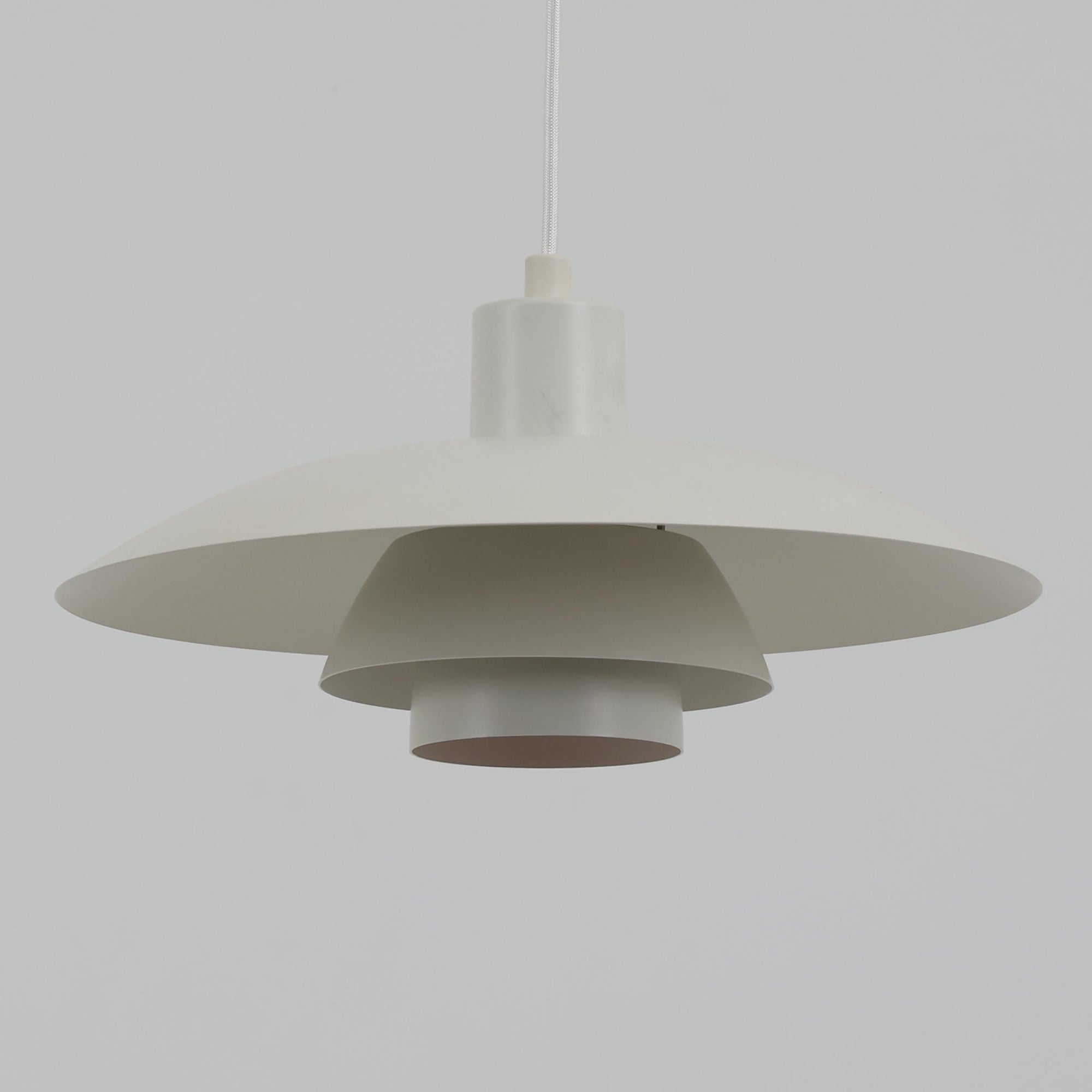 北欧より買い付けたLouis Poulsen社製「PH4」は、Poul Henningsenによる名作照明で、直径40cmの程よいサイズとアルミの軽やかな質感が魅力です。PH5と並ぶ人気を誇り、3枚シェード構造が光を柔らかく拡散し落ち着いた空間を演出します。経年の風合いも楽しめ、ダイニングやリビング、書斎や寝室まで幅広く活躍するビンテージ品です。