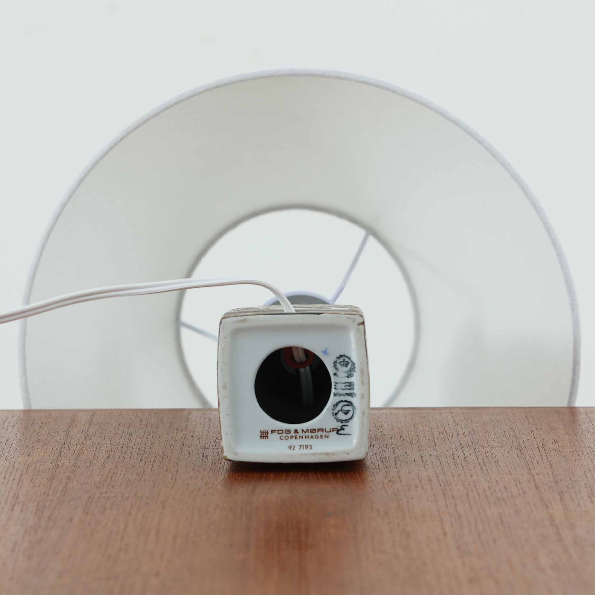 Nils Thorssonがデザインし、Royal Copenhagen社から発表された「BACA」シリーズのテーブルランプは、高さ38cmのバランスの取れたサイズ感で、北欧ビンテージらしい存在感を放ちます。陶磁器製のベースには細やかな装飾模様が施され、グラフィカルでありながら落ち着いた色調が空間に洗練された雰囲気を添えます。リネンシェードを透過する柔らかな光が温もりを演出し、リビングやベッドサイドに最適です。年月を経て深みを増した質感と工芸的な美しさを楽しめる一点物です。