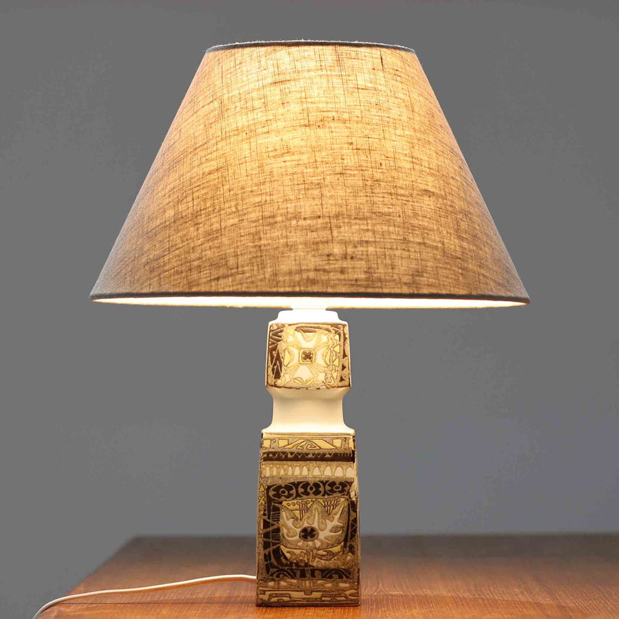 Nils Thorssonがデザインし、Royal Copenhagen社から発表された「BACA」シリーズのテーブルランプは、高さ38cmのバランスの取れたサイズ感で、北欧ビンテージらしい存在感を放ちます。陶磁器製のベースには細やかな装飾模様が施され、グラフィカルでありながら落ち着いた色調が空間に洗練された雰囲気を添えます。リネンシェードを透過する柔らかな光が温もりを演出し、リビングやベッドサイドに最適です。年月を経て深みを増した質感と工芸的な美しさを楽しめる一点物です。