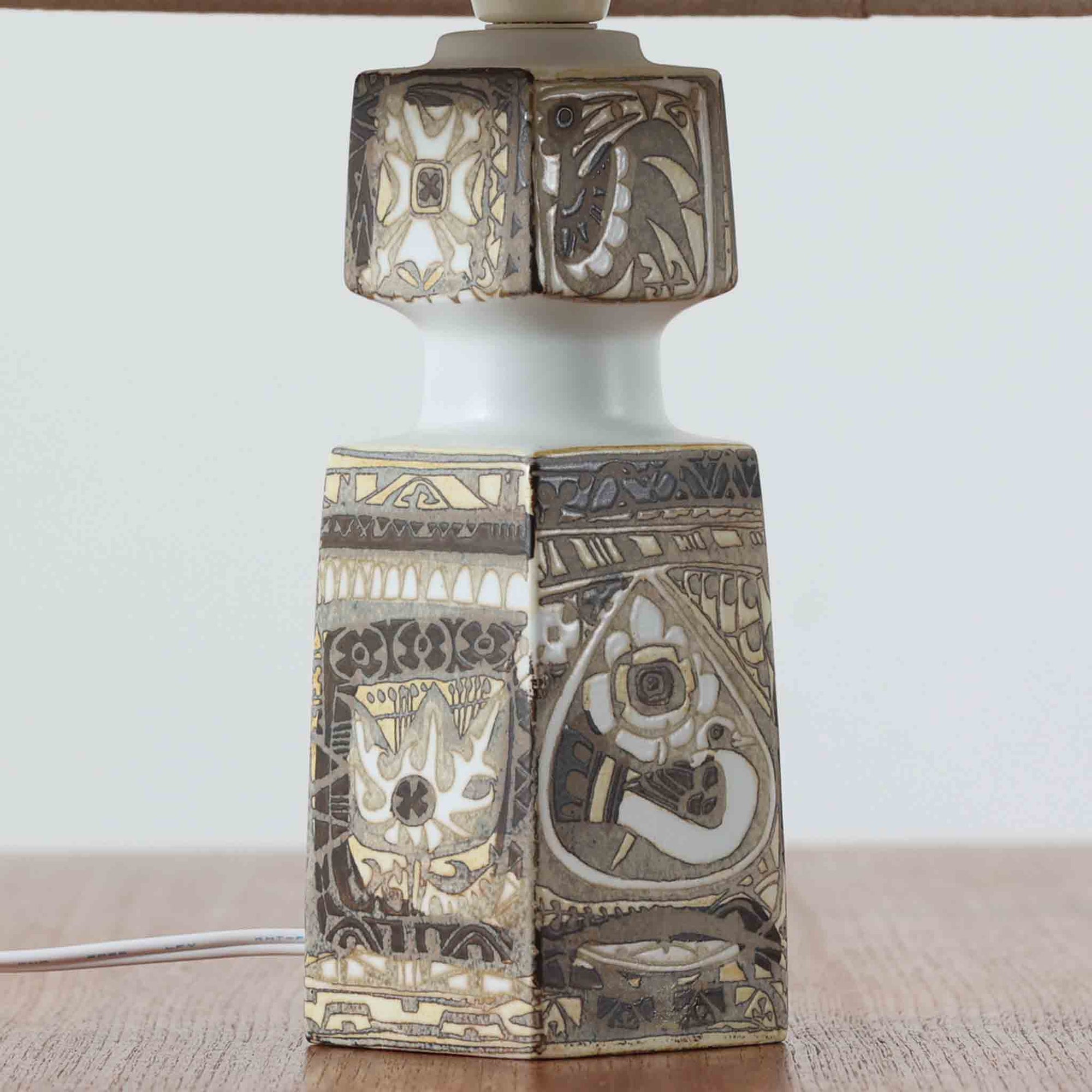 Nils Thorssonがデザインし、Royal Copenhagen社から発表された「BACA」シリーズのテーブルランプは、高さ38cmのバランスの取れたサイズ感で、北欧ビンテージらしい存在感を放ちます。陶磁器製のベースには細やかな装飾模様が施され、グラフィカルでありながら落ち着いた色調が空間に洗練された雰囲気を添えます。リネンシェードを透過する柔らかな光が温もりを演出し、リビングやベッドサイドに最適です。年月を経て深みを増した質感と工芸的な美しさを楽しめる一点物です。