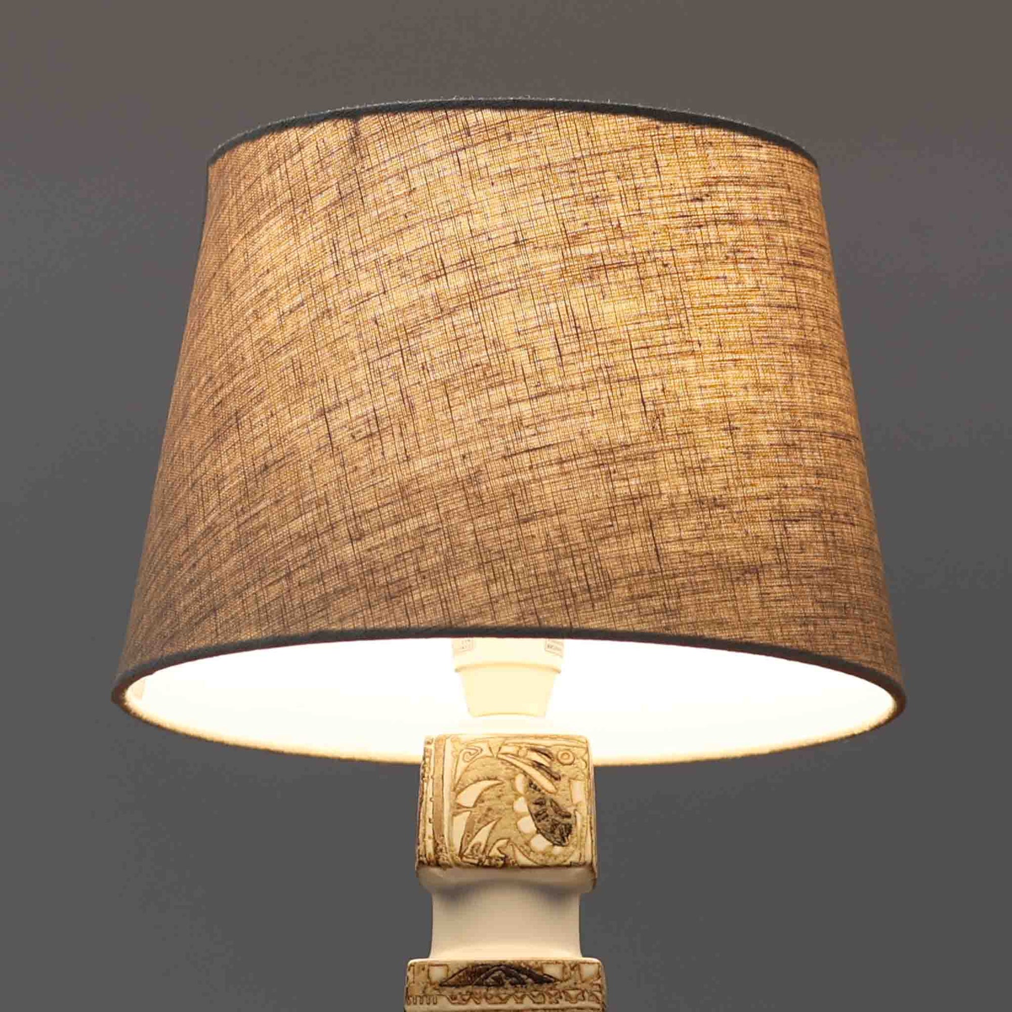 Nils Thorssonがデザインし、Royal Copenhagen社から発表された「BACA」シリーズのテーブルランプは、高さ39cmのバランスの取れたサイズ感で、北欧ビンテージらしい存在感を放ちます。陶磁器製のベースには細やかな装飾模様が施され、グラフィカルでありながら落ち着いた色調が空間に洗練された雰囲気を添えます。リネンシェードを透過する柔らかな光が温もりを演出し、リビングやベッドサイドに最適です。年月を経て深みを増した質感と工芸的な美しさを楽しめる一点物です。