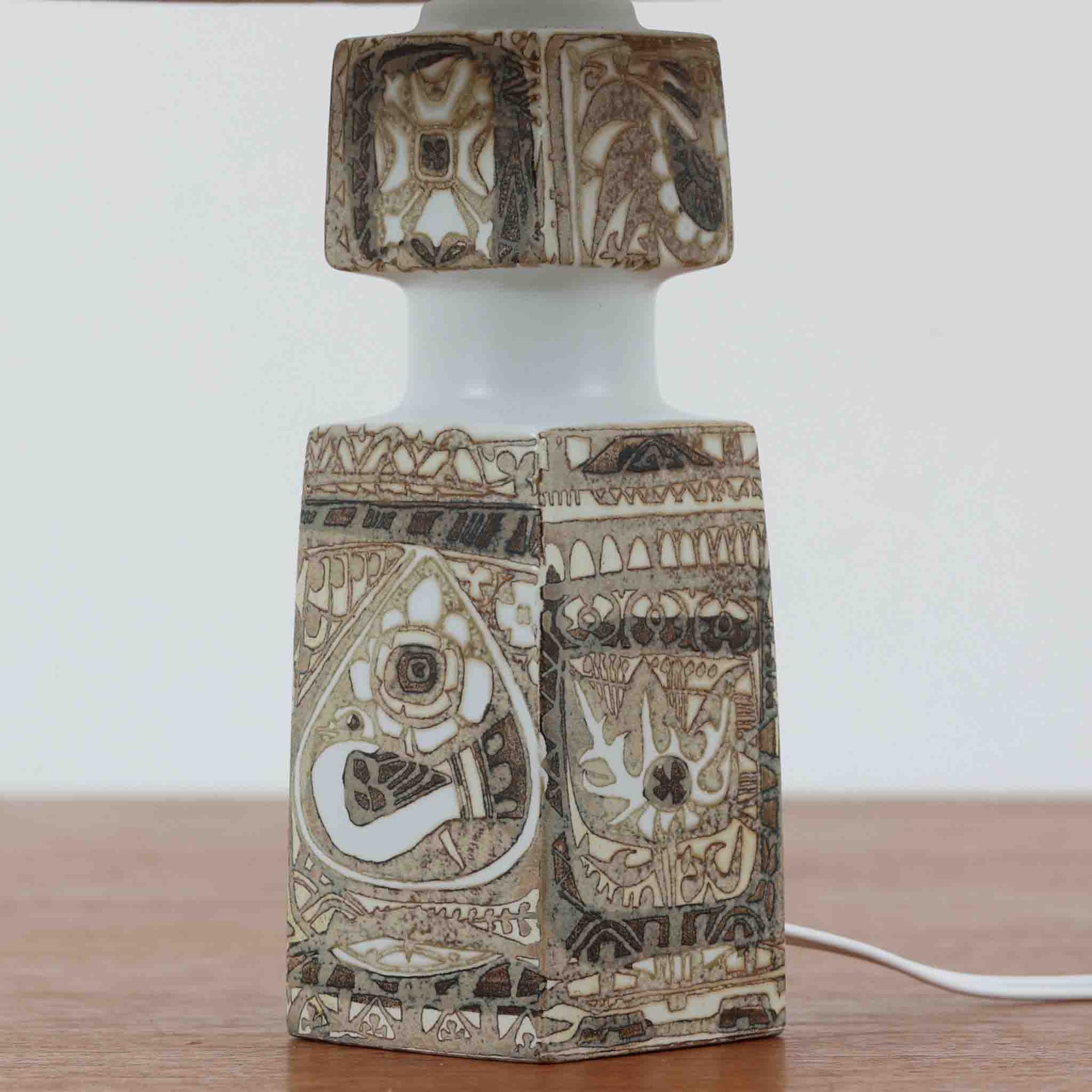 Nils Thorssonがデザインし、Royal Copenhagen社から発表された「BACA」シリーズのテーブルランプは、高さ39cmのバランスの取れたサイズ感で、北欧ビンテージらしい存在感を放ちます。陶磁器製のベースには細やかな装飾模様が施され、グラフィカルでありながら落ち着いた色調が空間に洗練された雰囲気を添えます。リネンシェードを透過する柔らかな光が温もりを演出し、リビングやベッドサイドに最適です。年月を経て深みを増した質感と工芸的な美しさを楽しめる一点物です。