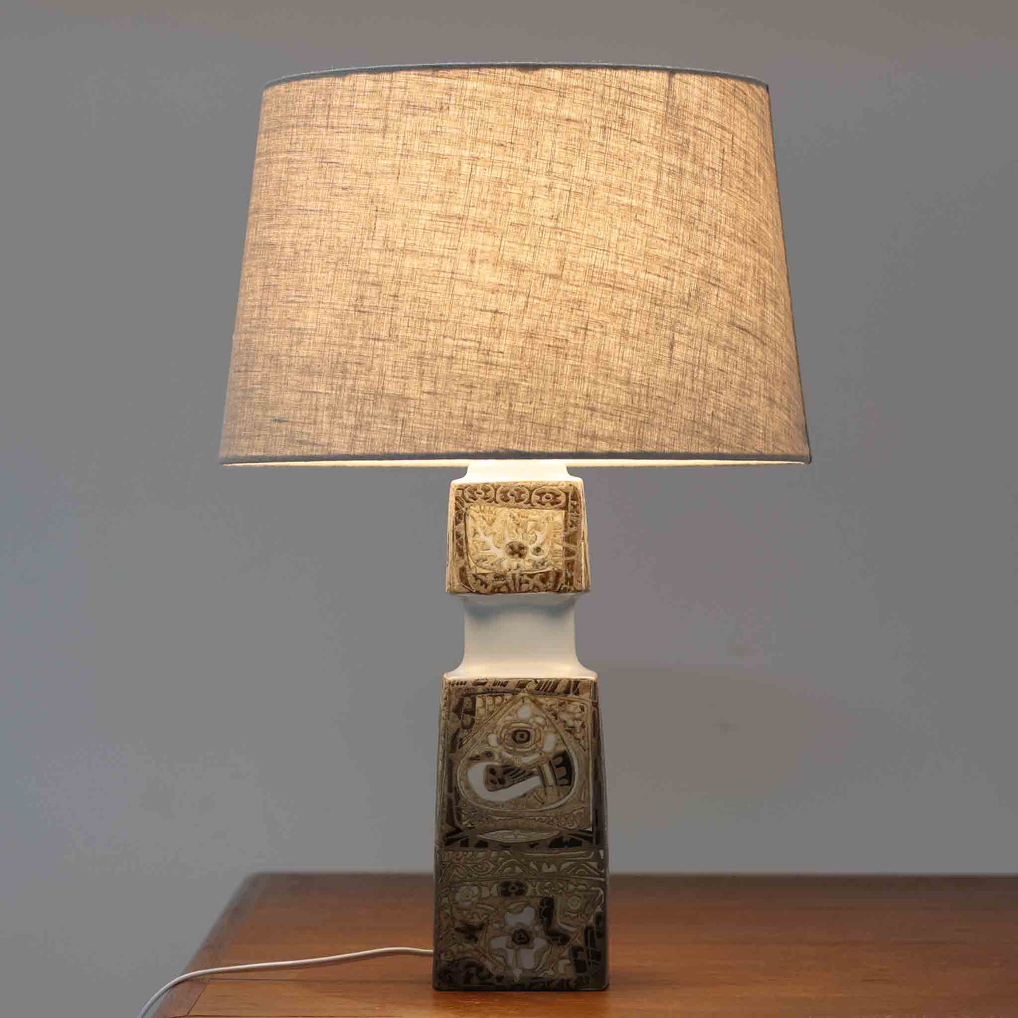 Nils ThorssonによるRoyal Copenhagen社のBACAシリーズのテーブルランプは、高さ50cmと大ぶりで存在感のあるビンテージアイテムです。陶磁器のベースにはトールソンらしい細密な装飾パターンが施され、幾何学的でありながら有機的なモチーフが調和し、芸術性を感じさせます。リネンシェードを透す光は柔らかく広がり、リビングや寝室を温かく包み込みます。年月を経た釉薬の風合いとクラフト感が、北欧ビンテージならではの魅力を引き立てる逸品です。