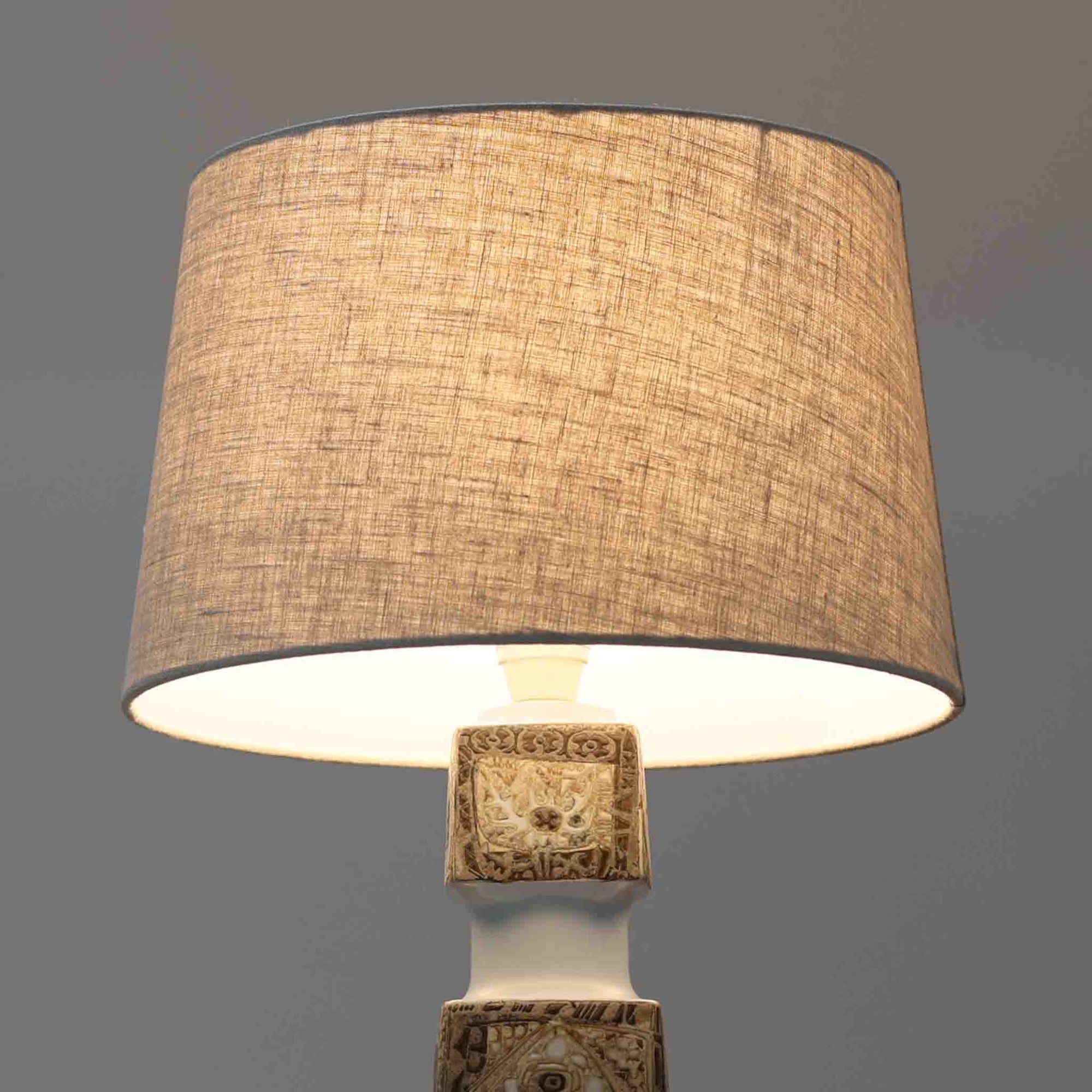 Nils ThorssonによるRoyal Copenhagen社のBACAシリーズのテーブルランプは、高さ50cmと大ぶりで存在感のあるビンテージアイテムです。陶磁器のベースにはトールソンらしい細密な装飾パターンが施され、幾何学的でありながら有機的なモチーフが調和し、芸術性を感じさせます。リネンシェードを透す光は柔らかく広がり、リビングや寝室を温かく包み込みます。年月を経た釉薬の風合いとクラフト感が、北欧ビンテージならではの魅力を引き立てる逸品です。