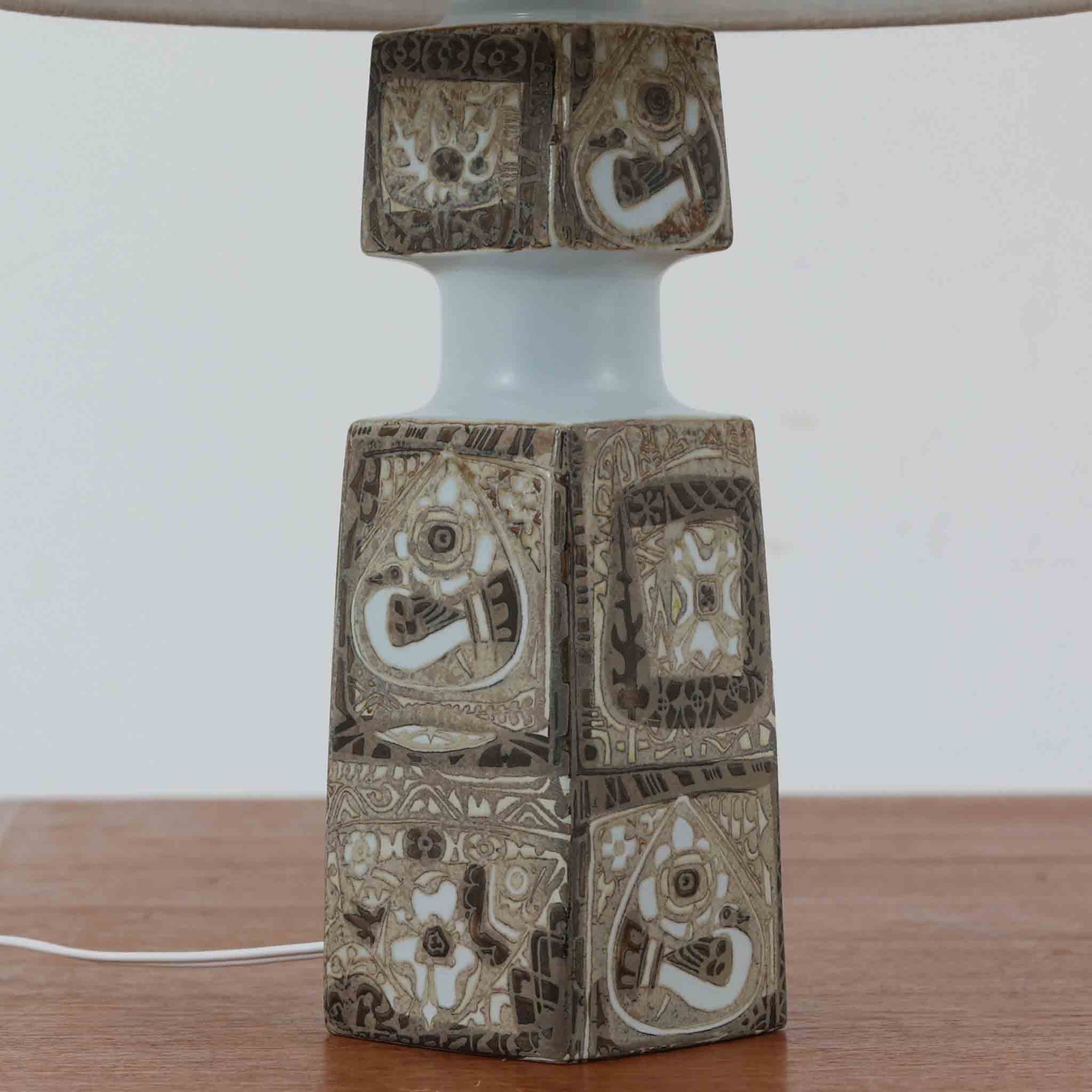 Nils ThorssonによるRoyal Copenhagen社のBACAシリーズのテーブルランプは、高さ50cmと大ぶりで存在感のあるビンテージアイテムです。陶磁器のベースにはトールソンらしい細密な装飾パターンが施され、幾何学的でありながら有機的なモチーフが調和し、芸術性を感じさせます。リネンシェードを透す光は柔らかく広がり、リビングや寝室を温かく包み込みます。年月を経た釉薬の風合いとクラフト感が、北欧ビンテージならではの魅力を引き立てる逸品です。