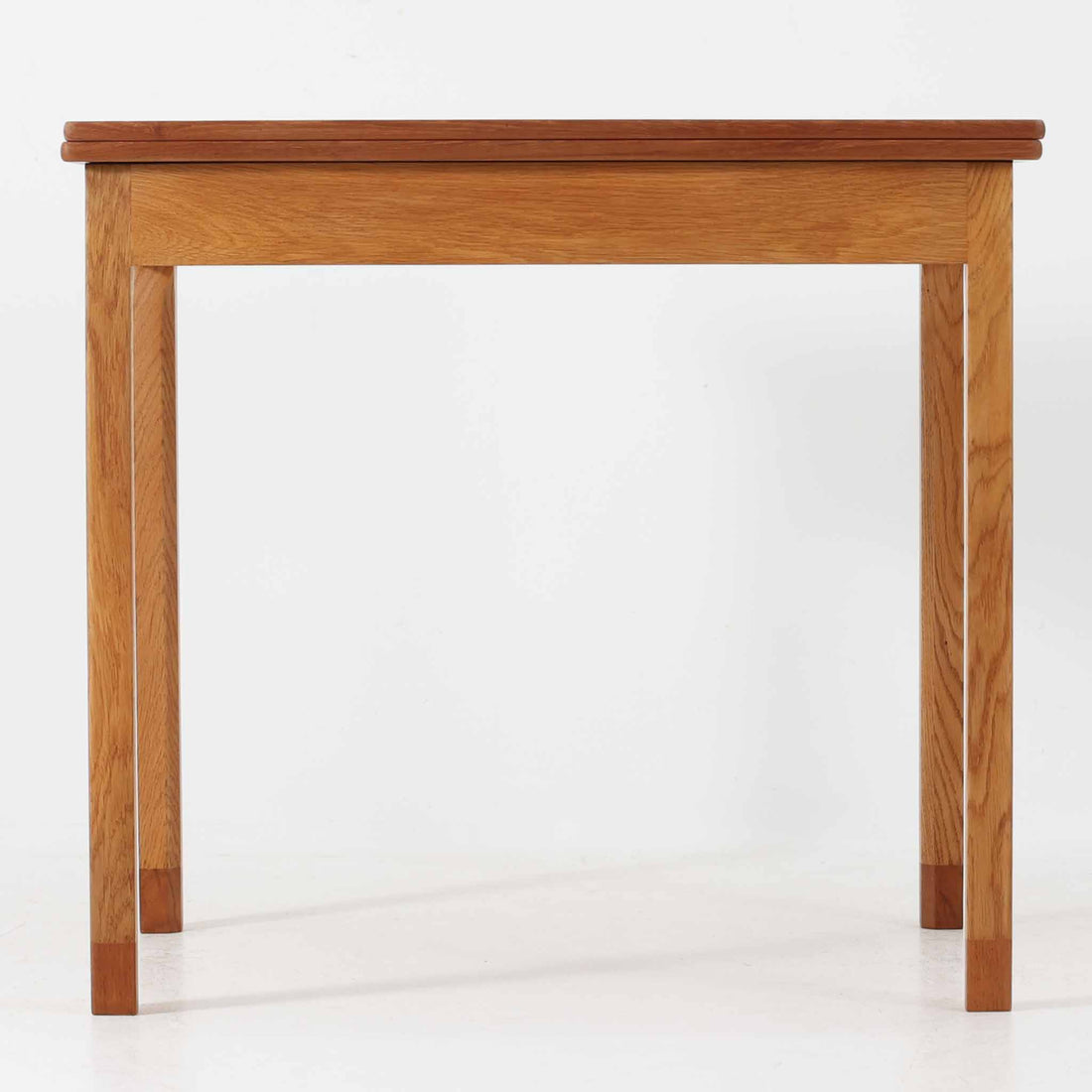 Borge Mogensen（ボーエ・モーエンセン）がSoborgのために手掛けた「Folding table」は、チーク材の天板とオーク材の脚部を組み合わせた温かみある佇まいが魅力のダイニングテーブルで、中央の蝶番を開閉して幅80～120cmへと柔軟に調整できる構造が特徴です。内部にはモーエンセン家具らしい実用性を備えた収納スペースが設けられ、ゲームテーブルとして親しまれてきた背景を感じさせます。経年により深まった木肌の風合いがビンテージならではの味わいをまとい、ダイニングやワークスペースのサブテーブルとしても多用途に活躍する一台です。また、裏面には「SKM」の刻印が確認でき、スウェーデン軍（Svenska KrigsMakten）の備品として使用されていたことを示しています。