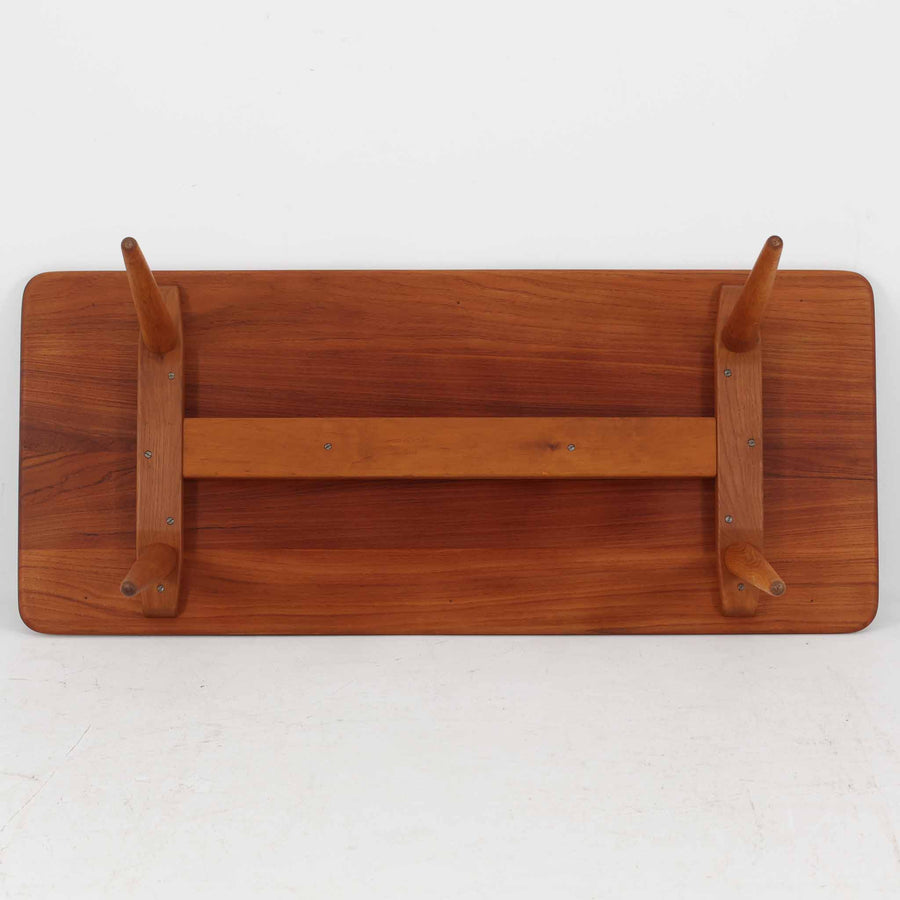 Hans J. Wegner（ハンス・J・ウェグナー）によるAndreas Tuck社製のセンターテーブル「AT11」です。幅130cmの広々とした天板はチーク無垢材を使用し、縁には繊細な面取り加工が施され、柔らかな印象を与えます。脚部には堅牢なオーク無垢材が用いられ、軽やかなテーパードデザインが北欧家具らしいバランスの良さを感じさせます。さらに脚のネジ部分まで木製で仕上げられており、細部に至るまで職人技が光る逸品です。脚は取り外し可能な構造で、輸送や設置も容易です。シンプルでありながら素材の美しさが際立ち、経年変化による深みを増した木肌がビンテージならではの存在感を放ちます。リビングの中心に置いて使うことで、空間に上質な雰囲気を添える一台です。
