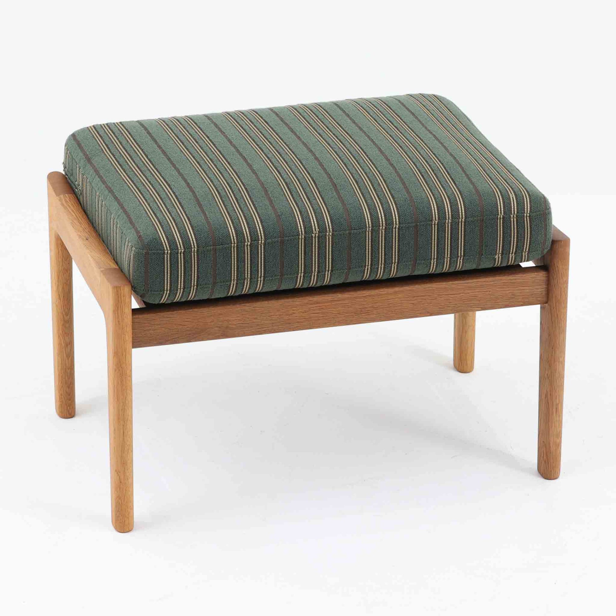 Hans J. Wegnerがデザインし、Getamaが製作したGE290オットマンの希少なサイドテーブル兼用タイプです。オーク材の美しい木目を活かしたフレームは、丸みを帯びたアーム状の意匠が印象的で、安定感のある堅牢な構造が魅力。クッションを外せばトレーテーブルとしても使用できる実用的な設計です。本品はGetama社の刻印が入る以前の古いタイプで、初期モデルならではの佇まいも価値を高めています。ラウンジチェアと合わせてはもちろん、単体でも存在感を放つ北欧ビンテージの逸品です。クッション内部にはビンテージ品ならではのスプリングが内包されています。