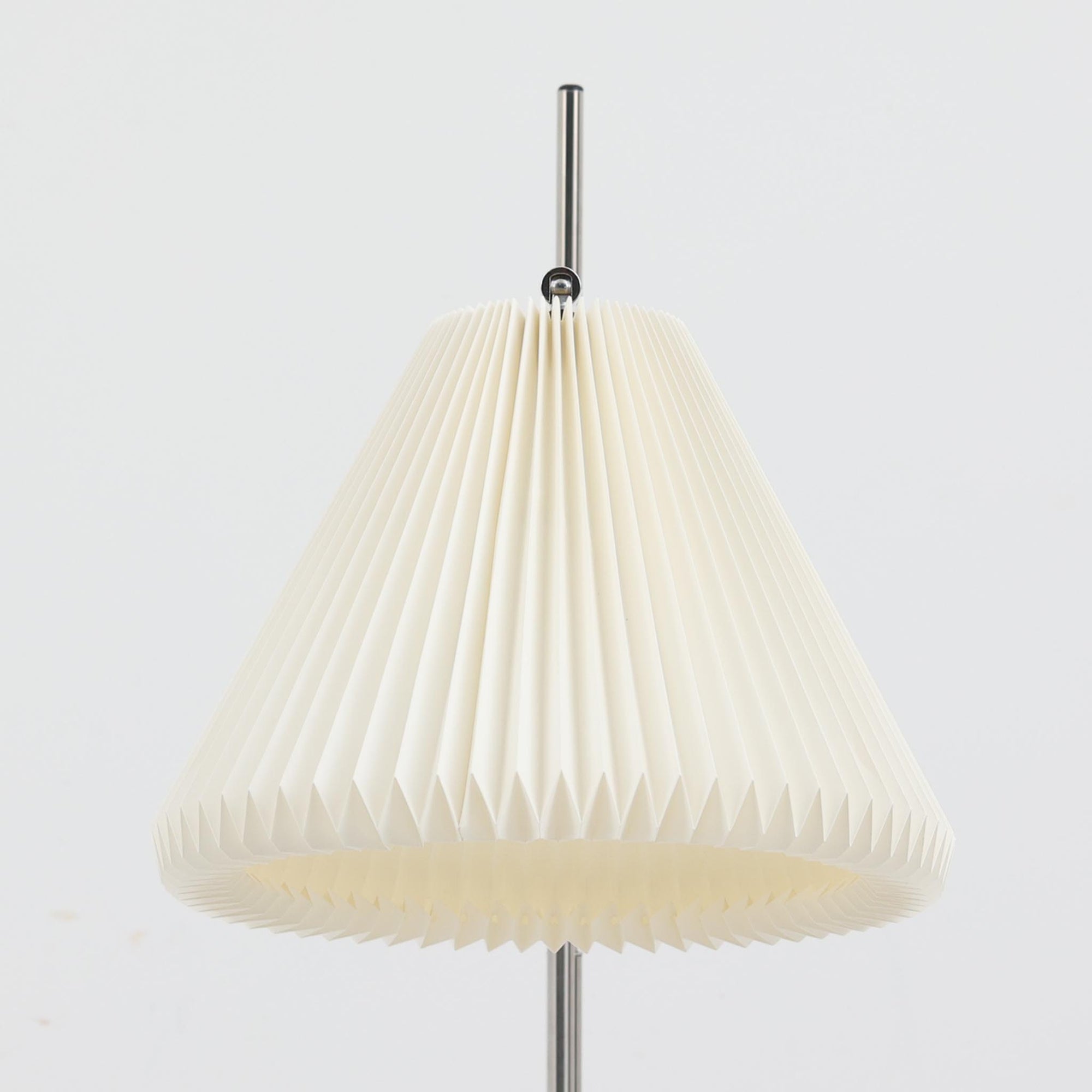 Michael Bang（マイケル・バン）によるデザインで、Le Klint（レ・クリント）から発表されたフロアランプModel 321です。高さ131cmのスチール製フレームは、無駄のない直線的なフォルムと精巧なディテールが際立ち、モダンな空間に調和します。特徴的なスライド機構によりランプの高さを調整でき、読書灯から間接照明まで幅広い用途に対応。ハンドクラフトによるプリーツシェードは柔らかい光を生み出し、北欧ビンテージならではの温もりと機能美を感じさせます。