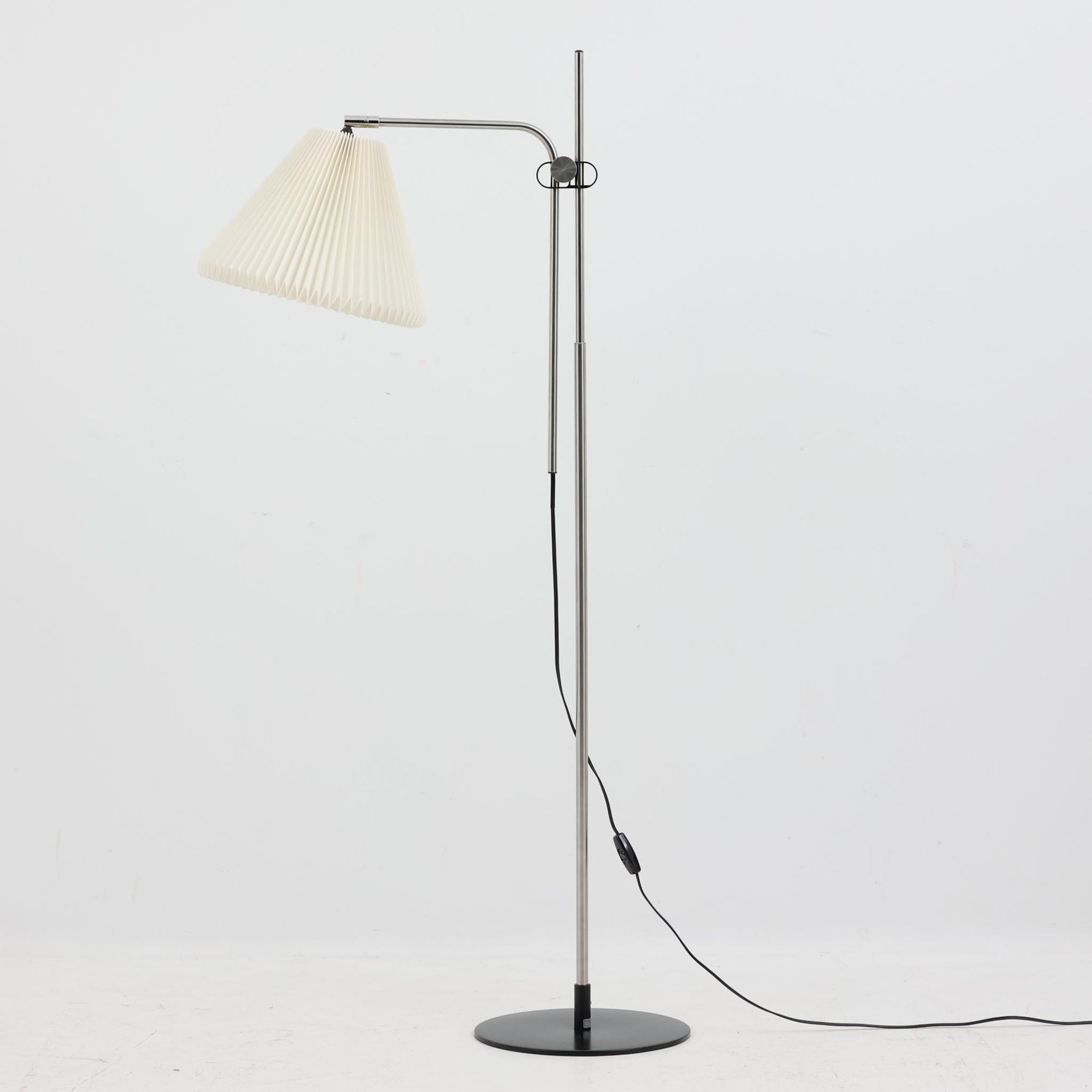 Michael Bang（マイケル・バン）によるデザインで、Le Klint（レ・クリント）から発表されたフロアランプModel 321です。高さ131cmのスチール製フレームは、無駄のない直線的なフォルムと精巧なディテールが際立ち、モダンな空間に調和します。特徴的なスライド機構によりランプの高さを調整でき、読書灯から間接照明まで幅広い用途に対応。ハンドクラフトによるプリーツシェードは柔らかい光を生み出し、北欧ビンテージならではの温もりと機能美を感じさせます。