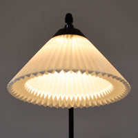 Flemming Agger（フレミング・アガー）がデザインし、Le Klint（レ・クリント）社より発表されたモデル368のフロアランプです。高さ145cmのスマートなフォルムに、ブラックスチールのアームと美しいプリーツシェードが組み合わされ、北欧モダンらしい端正な佇まいを見せます。プラスチックシート製のシェードは光を柔らかく透過し、リビングやベッドサイドに心地よい明かりをもたらします。シンプルながらも計算された構造は職人技が感じられ、ビンテージならではの希少性と存在感を併せ持つ逸品です。