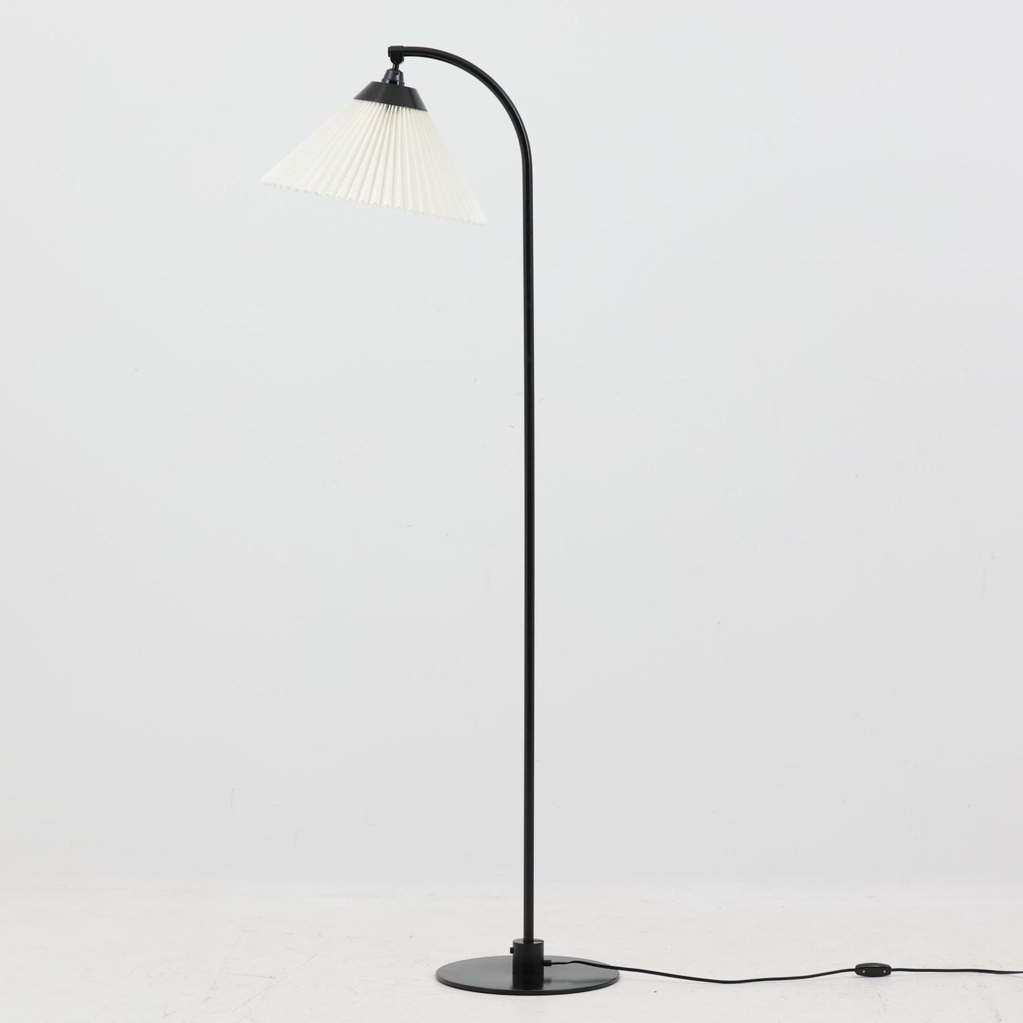 Flemming Agger（フレミング・アガー）がデザインし、Le Klint（レ・クリント）社より発表されたモデル368のフロアランプです。高さ145cmのスマートなフォルムに、ブラックスチールのアームと美しいプリーツシェードが組み合わされ、北欧モダンらしい端正な佇まいを見せます。プラスチックシート製のシェードは光を柔らかく透過し、リビングやベッドサイドに心地よい明かりをもたらします。シンプルながらも計算された構造は職人技が感じられ、ビンテージならではの希少性と存在感を併せ持つ逸品です。