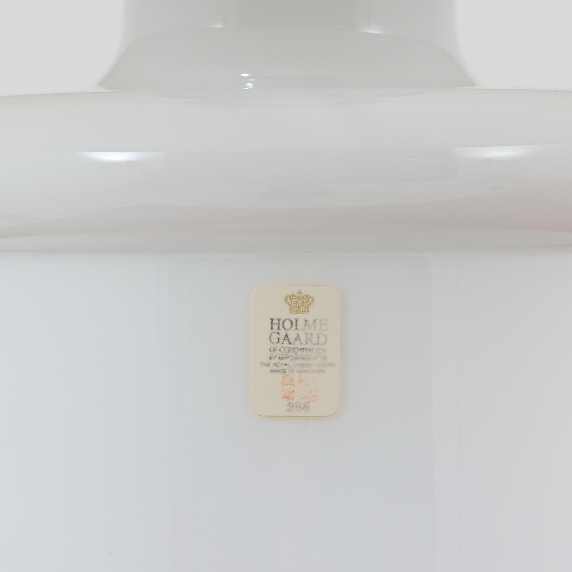 Sidse Wernerがデザインし、Holmegaard社より製造された「Apoteker」テーブルランプは、高さ46cmの堂々としたサイズ感と、白色ガラスの透明感が魅力の一品です。シリンダー状のフォルムにさりげなく入ったライン装飾が、シンプルながらも奥行きを感じさせるデザインとなっています。ガラス特有の柔らかな光の反射とリネンシェードを透過する穏やかな灯りは、リビングや寝室に落ち着いた雰囲気をもたらします。北欧ビンテージならではの洗練された存在感を楽しめる逸品です。