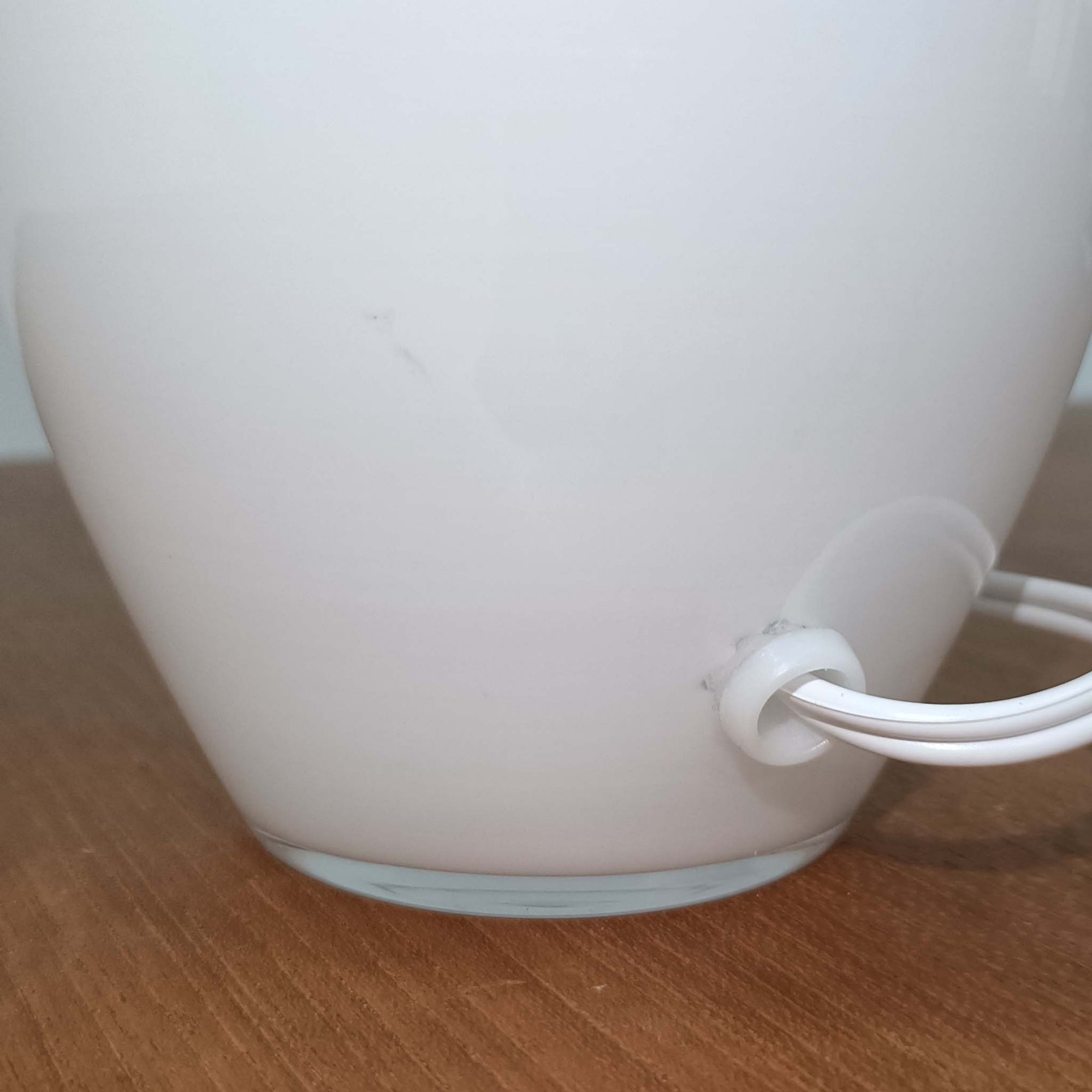 デンマークの老舗ガラスメーカー、Holmegaard（ホルムガード）社による「Cocoon」モデルのテーブルランプです。デザイナーはPeter Svarrer（ピーター・スヴァレ）で、彼らしい滑らかな曲線と透明感のあるフォルムが美しく表現されています。乳白色のガラスベースは光をやわらかく反射し、リネンシェードを通して穏やかな灯りを広げます。北欧らしいミニマルで洗練されたデザインは、ベッドサイドやリビングなどに上質な雰囲気をもたらしてくれます。