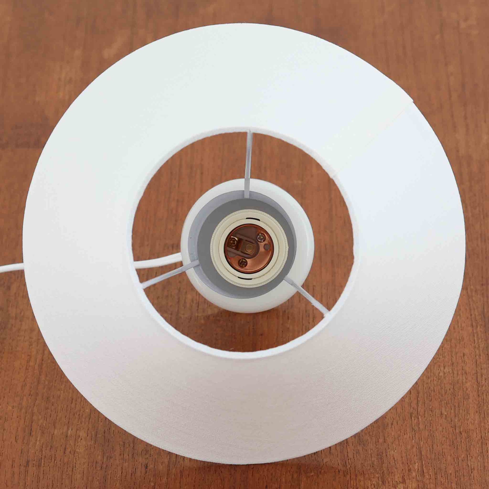 Sidse Werner（シセ・ヴェルナー）がデザインし、Holmegaard（ホルムガード）より製造されたテーブルランプ「Apoteker」です。高さ29cmと小ぶりなサイズで、艶やかなホワイトガラスのベースが柔らかな印象を与えます。リネンシェードを通した光は優しく拡散し、ナチュラルな雰囲気を演出。シンプルでありながら彫刻的なフォルムが存在感を放ち、ベッドサイドやデスク、リビングのサイドテーブルなど様々な空間で活躍します。北欧デザインの温もりを感じられるビンテージ照明です。