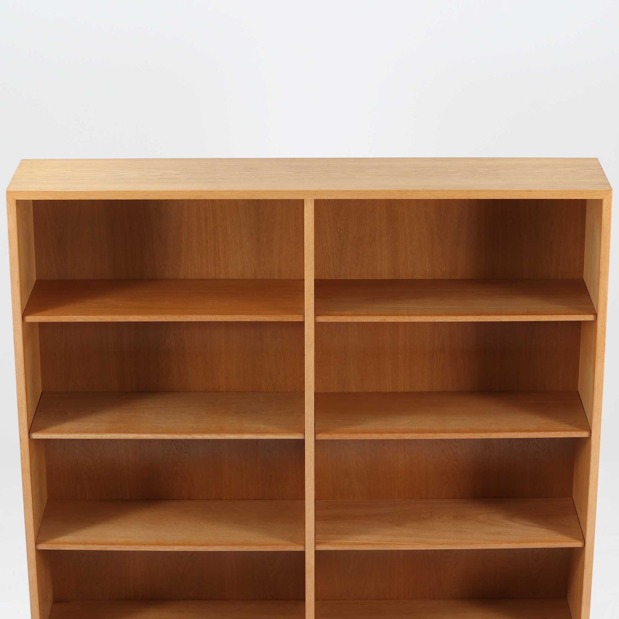 Borge Mogensenがデザインし、Karl Andersson &amp; Sonerが製作した幅135cmのブックシェルフです。上質なオーク材を用いた無駄のない直線的な構成が特徴で、中央の仕切りにより整然とした収納を実現しています。固定棚による堅牢な構造は、日常使いの書籍や資料をしっかりと支え、空間に落ち着いた存在感をもたらします。素材の質感を活かした端正な佇まいは、リビングや書斎、オフィスにも自然に馴染み、北欧ビンテージならではの実直な美しさと経年変化の魅力を感じられる一品です。