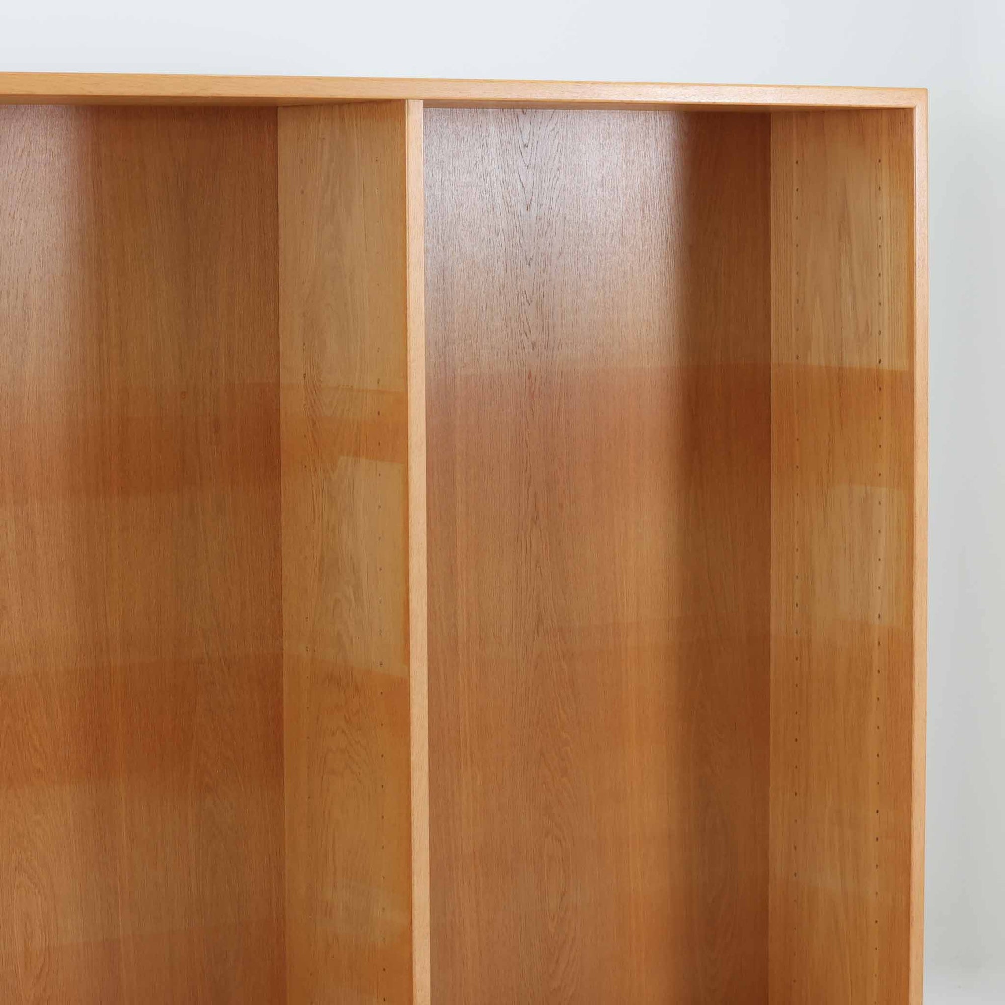 Borge Mogensenがデザインし、Karl Andersson &amp; Sonerが製作した幅135cmのブックシェルフです。上質なオーク材を用いた無駄のない直線的な構成が特徴で、中央の仕切りにより整然とした収納を実現しています。固定棚による堅牢な構造は、日常使いの書籍や資料をしっかりと支え、空間に落ち着いた存在感をもたらします。素材の質感を活かした端正な佇まいは、リビングや書斎、オフィスにも自然に馴染み、北欧ビンテージならではの実直な美しさと経年変化の魅力を感じられる一品です。