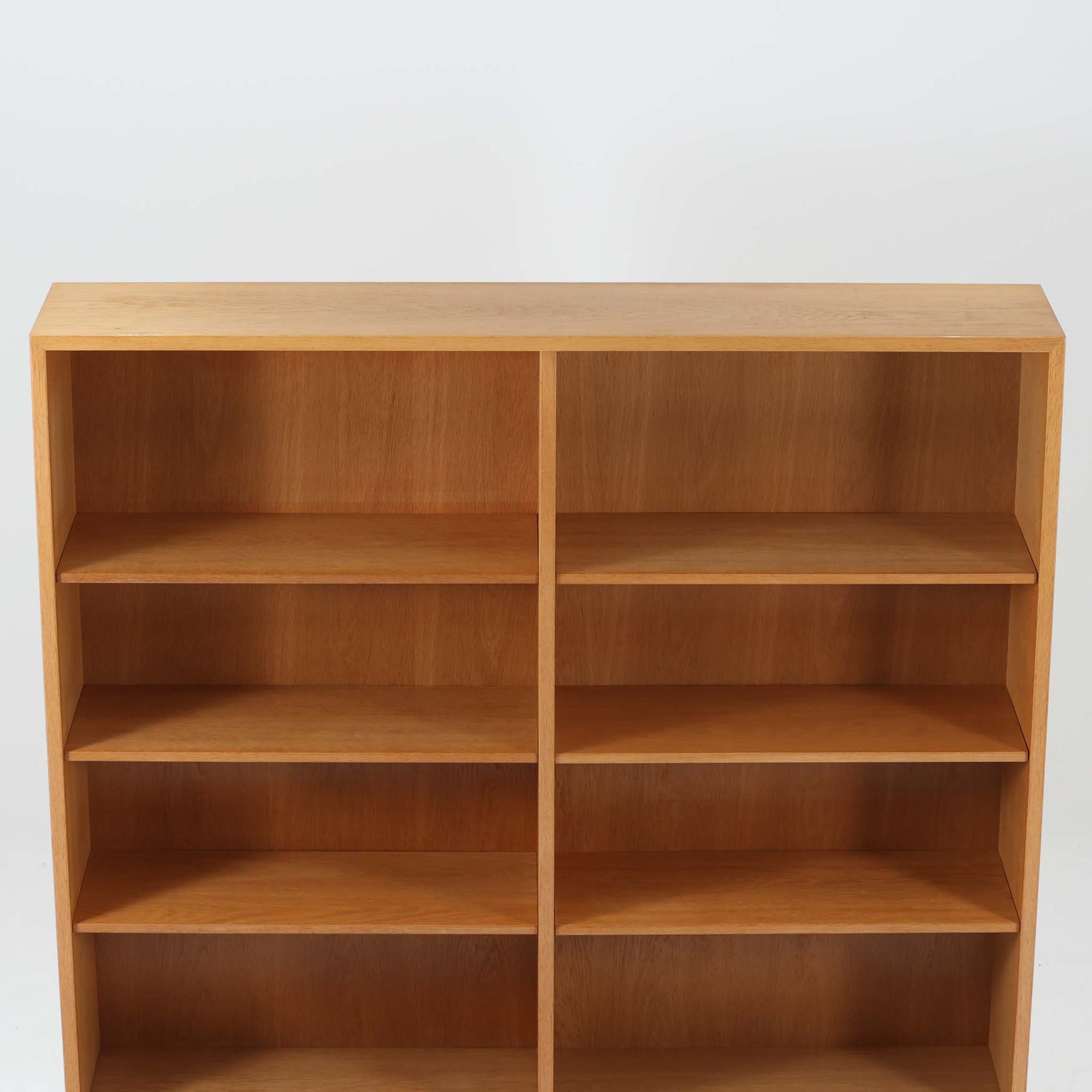 Borge Mogensenがデザインし、Karl Andersson &amp; Sonerが製作した幅135cmのブックシェルフです。上質なオーク材を用いた無駄のない直線的な構成が特徴で、中央の仕切りにより整然とした収納を実現しています。固定棚による堅牢な構造は、日常使いの書籍や資料をしっかりと支え、空間に落ち着いた存在感をもたらします。素材の質感を活かした端正な佇まいは、リビングや書斎、オフィスにも自然に馴染み、北欧ビンテージならではの実直な美しさと経年変化の魅力を感じられる一品です。