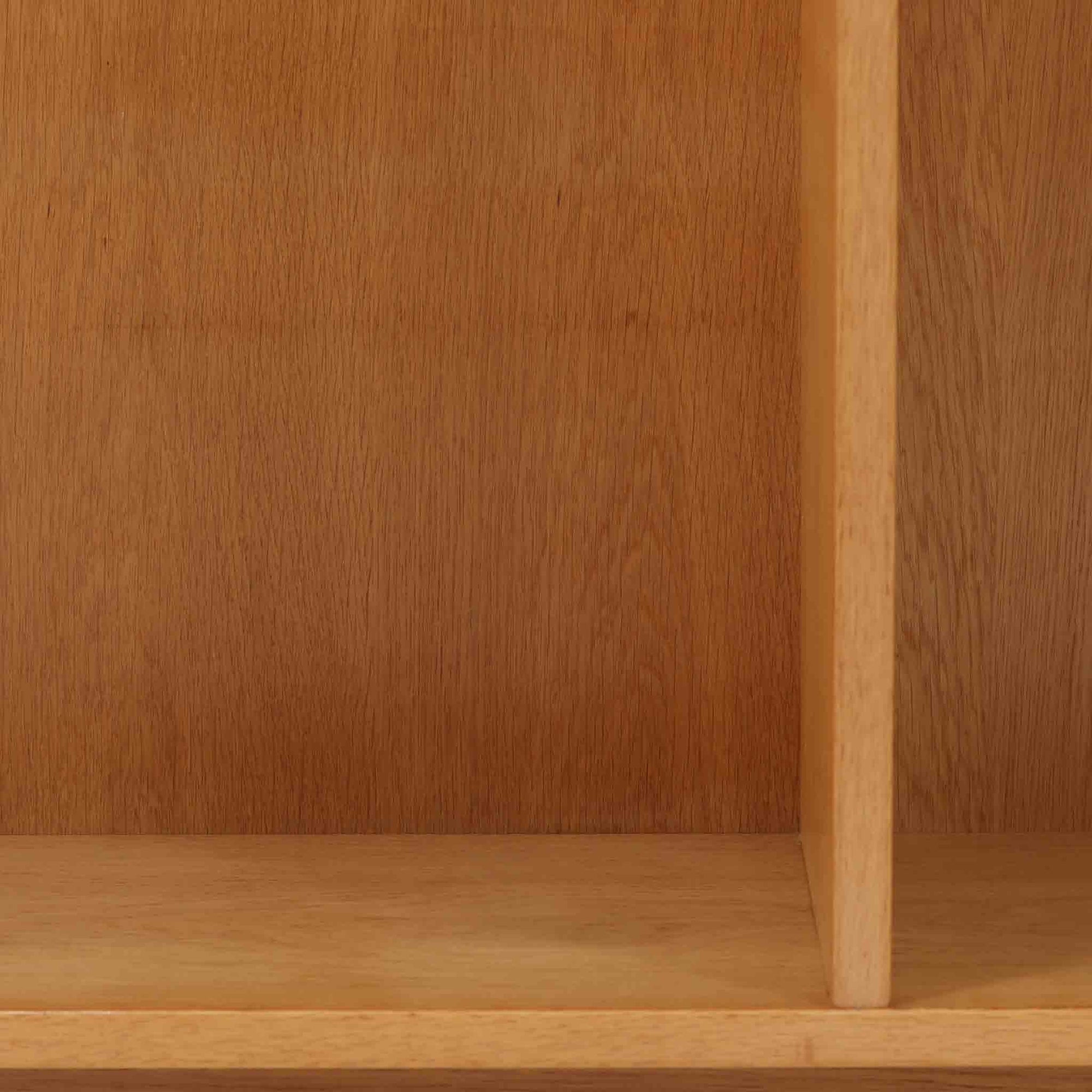 Borge Mogensenがデザインし、Karl Andersson &amp; Sonerが製作した幅135cmのブックシェルフです。上質なオーク材を用いた無駄のない直線的な構成が特徴で、中央の仕切りにより整然とした収納を実現しています。固定棚による堅牢な構造は、日常使いの書籍や資料をしっかりと支え、空間に落ち着いた存在感をもたらします。素材の質感を活かした端正な佇まいは、リビングや書斎、オフィスにも自然に馴染み、北欧ビンテージならではの実直な美しさと経年変化の魅力を感じられる一品です。