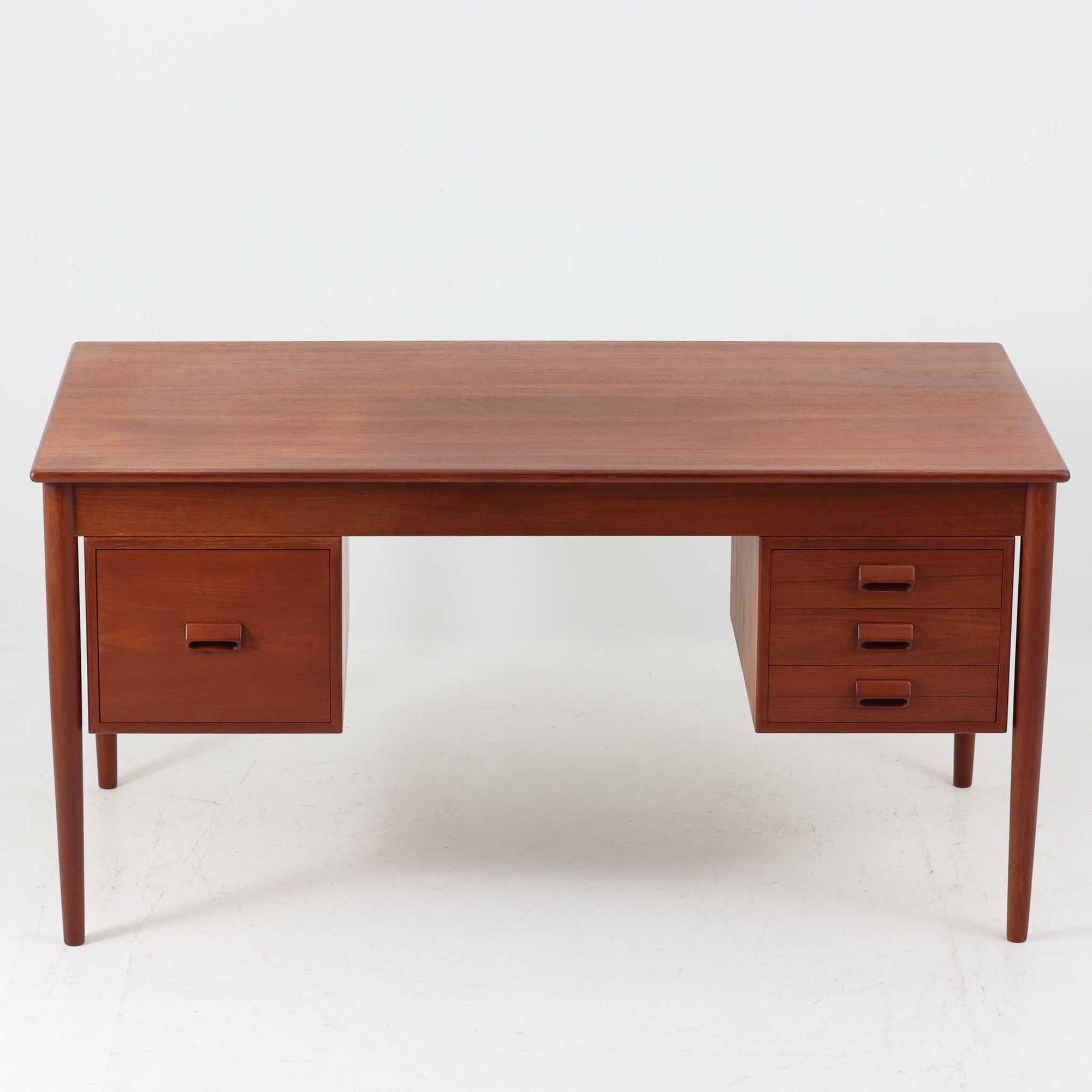 Borge MogensenがSoborg Mobler社のためにデザインしたModel 130の両袖デスクです。良質なチーク材を全面に使用した仕様は珍しく、温かみと重厚感を兼ね備えています。右側には3杯の引き出し、左側には1杯の深型引き出しを備えた構成もスタンダードな3段＋2段タイプとは異なる希少なディテールです。幅146cmと程よいサイズ感で、書斎やオフィスに取り入れやすく、実用性と存在感を兼ね備えています。直線的で力強いフォルムはモーエンセンらしい機能美を体現し、経年により深みを増したチーク材の風合いが空間に格調を添えるビンテージデスクです。