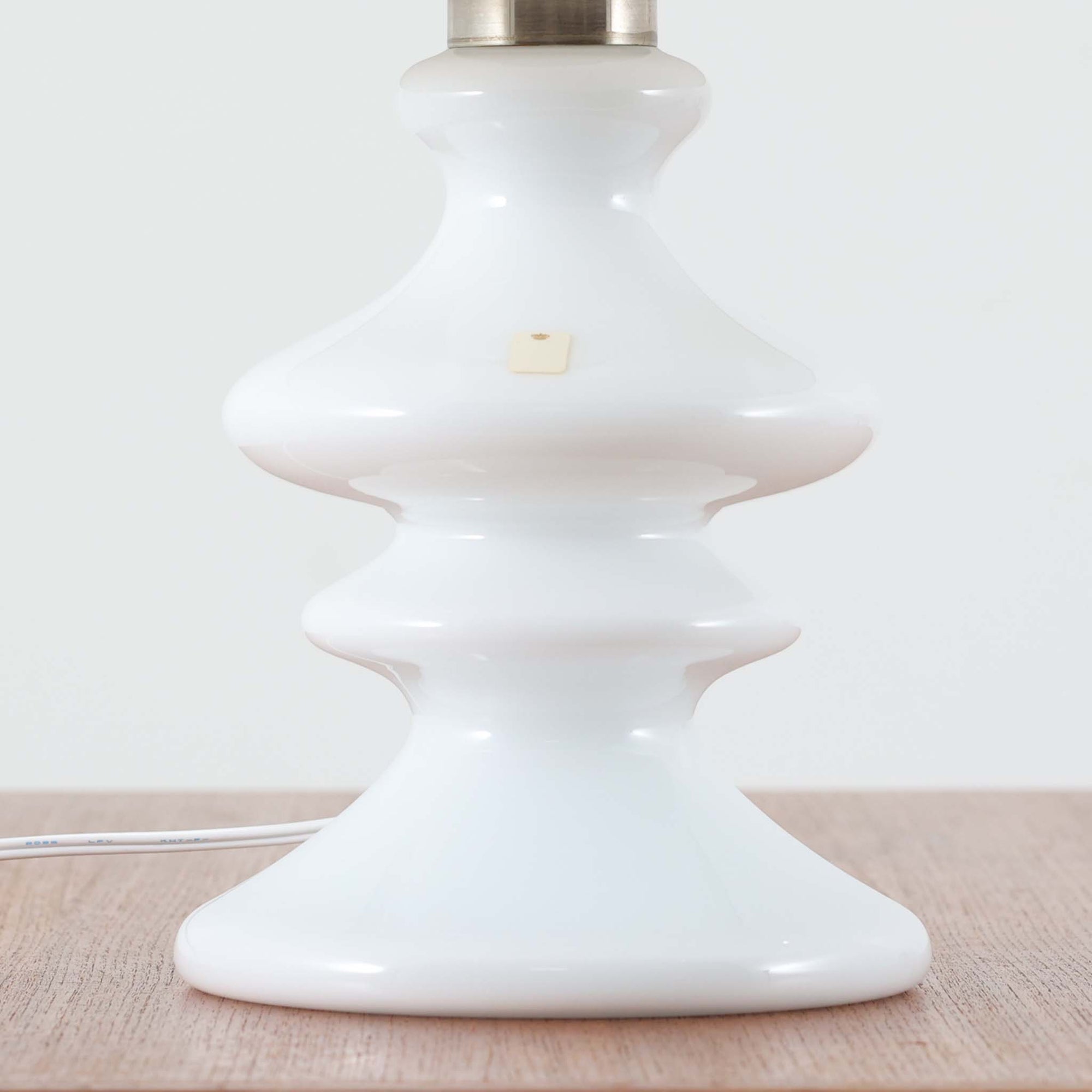 Per Lutken（ペア・ルッケン）によるデザイン、Holmegaard（ホルムガード）製のテーブルランプ「Mary」です。高さ44cmの存在感あるサイズで、滑らかな曲線を描くホワイトガラスのベースは柔らかい光沢を放ち、北欧らしい洗練された印象を与えます。シンプルなリネンシェードを通した光は温かみのある雰囲気を演出し、リビングやベッドサイドに心地よい灯りを添えます。北欧モダンデザインの魅力と職人技が息づくビンテージ照明です。