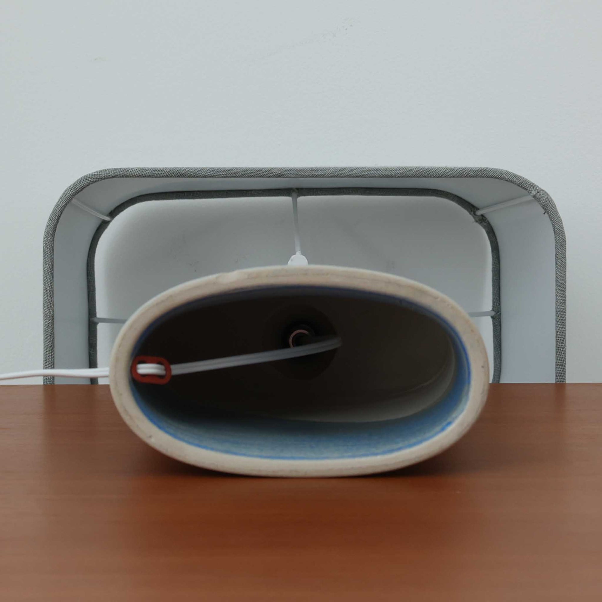 こちらのテーブルランプは、陶磁器ベースに淡いパープルやブルーを溶け合わせたような独特の釉薬表情が魅力で、ビンテージならではの柔らかなグラデーションが優しい存在感を放つ一品です。細く立ち上がる支柱にリネンシェードを組み合わせたシンプルな構造は安定感があり、点灯時にはシェード越しに温かく穏やかな光が広がります。高さ46cmと扱いやすいサイズで、ベッドサイドやリビングのサイドテーブルにも取り入れやすく、北欧らしい静かな色彩と経年の味わいを楽しめるビンテージ照明です。