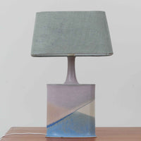 こちらのテーブルランプは、陶磁器ベースに淡いパープルやブルーを溶け合わせたような独特の釉薬表情が魅力で、ビンテージならではの柔らかなグラデーションが優しい存在感を放つ一品です。細く立ち上がる支柱にリネンシェードを組み合わせたシンプルな構造は安定感があり、点灯時にはシェード越しに温かく穏やかな光が広がります。高さ46cmと扱いやすいサイズで、ベッドサイドやリビングのサイドテーブルにも取り入れやすく、北欧らしい静かな色彩と経年の味わいを楽しめるビンテージ照明です。