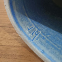 こちらのテーブルランプは、陶磁器ベースに淡いパープルやブルーを溶け合わせたような独特の釉薬表情が魅力で、ビンテージならではの柔らかなグラデーションが優しい存在感を放つ一品です。細く立ち上がる支柱にリネンシェードを組み合わせたシンプルな構造は安定感があり、点灯時にはシェード越しに温かく穏やかな光が広がります。高さ46cmと扱いやすいサイズで、ベッドサイドやリビングのサイドテーブルにも取り入れやすく、北欧らしい静かな色彩と経年の味わいを楽しめるビンテージ照明です。