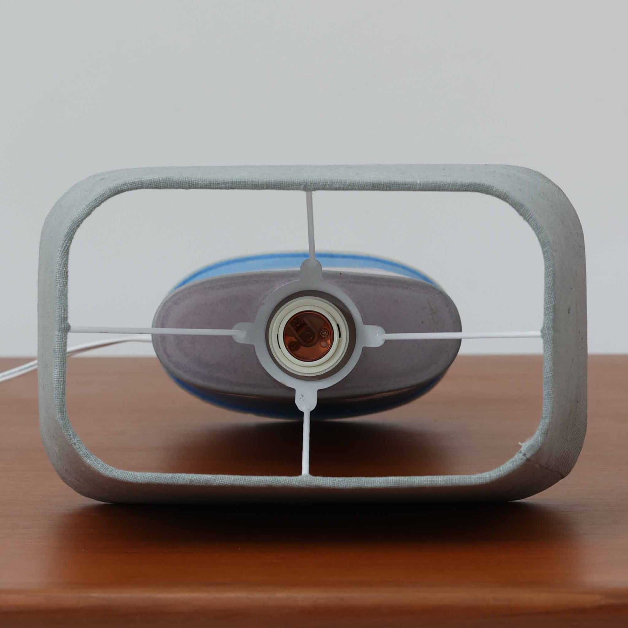 こちらのテーブルランプは、陶磁器ベースに淡いパープルやブルーを溶け合わせたような独特の釉薬表情が魅力で、ビンテージならではの柔らかなグラデーションが優しい存在感を放つ一品です。細く立ち上がる支柱にリネンシェードを組み合わせたシンプルな構造は安定感があり、点灯時にはシェード越しに温かく穏やかな光が広がります。高さ46cmと扱いやすいサイズで、ベッドサイドやリビングのサイドテーブルにも取り入れやすく、北欧らしい静かな色彩と経年の味わいを楽しめるビンテージ照明です。