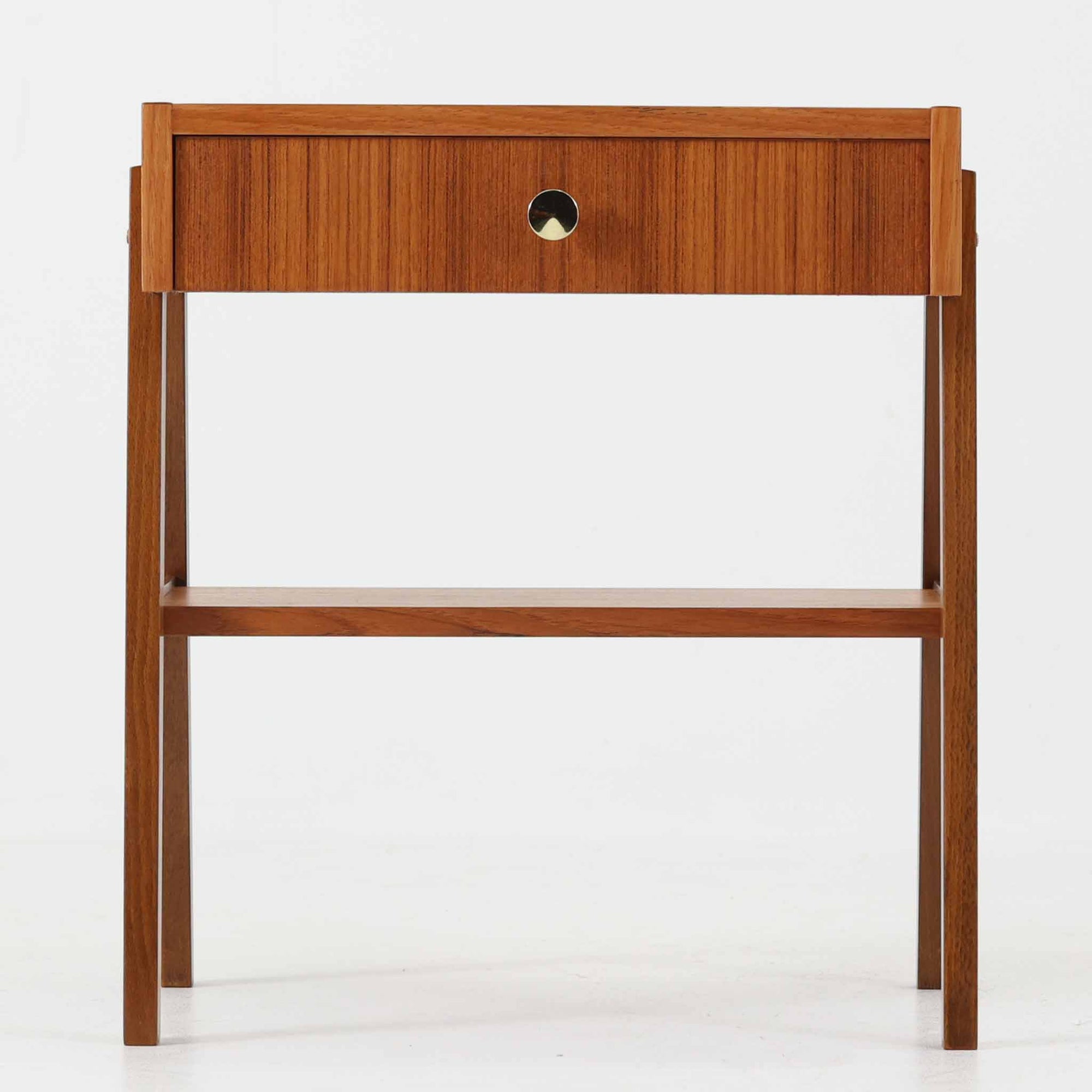 スウェーデン製のこちらのサイドチェストは、チーク材の美しい木目とビーチ材の脚部を組み合わせた軽やかな構成が魅力で、前板にあしらわれたゴールド色のメタルの取手が上品なアクセントを添える北欧ビンテージ品です。引き出しに加えて下段にはオープンシェルフが設けられ、ベッドサイドやリビングのサイドテーブルとして実用性高くお使いいただけます。細身のフレームでありながらしっかりとした造りで、経年により深まった木肌の風合いが空間に温かさと落ち着きをもたらす一台です。