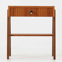 スウェーデン製のこちらのサイドチェストは、チーク材の美しい木目とビーチ材の脚部を組み合わせた軽やかな構成が魅力で、前板にあしらわれたゴールド色のメタルの取手が上品なアクセントを添える北欧ビンテージ品です。引き出しに加えて下段にはオープンシェルフが設けられ、ベッドサイドやリビングのサイドテーブルとして実用性高くお使いいただけます。細身のフレームでありながらしっかりとした造りで、経年により深まった木肌の風合いが空間に温かさと落ち着きをもたらす一台です。