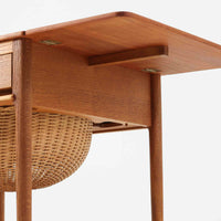 ハンス・J・ウェグナーが手がけ、Andreas Tuck社より製作されたAT33ソーイングテーブルは、天板を広げられる独創的な構造と実用性を兼ね備えた北欧ビンテージを代表する一台です。中央には引き出しと仕切り付き収納、下部にはラタンバスケットを備え、道具をすっきりと収められる設計が魅力。AT33は複数の素材構成で展開されたモデルですが、こちらは天板にチーク突板材、脚部にオーク無垢材を用いた仕様で、素材のコントラストと軽やかな佇まいが特徴です。異素材を巧みに組み合わせた構造と端正なプロポーションは、使うほどに職人技と経年変化の美しさを実感できます。