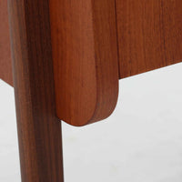 チーク材を用いた小ぶりなキャビネットは、直線を基調としつつ柔らかな丸みを持たせた側板と脚部のラインが印象的な北欧ビンテージ家具です。前板一枚で構成されたフラップ扉には掘り込み式の取っ手が設けられ、開閉時の所作も美しく、内部には実用的な収納棚を備えています。幅69cmと取り入れやすいサイズ感で、リビングや玄関、ベッドサイドの収納としても活躍し、経年により深みを増したチーク材の木目と職人技が静かな存在感を放つ一台です。