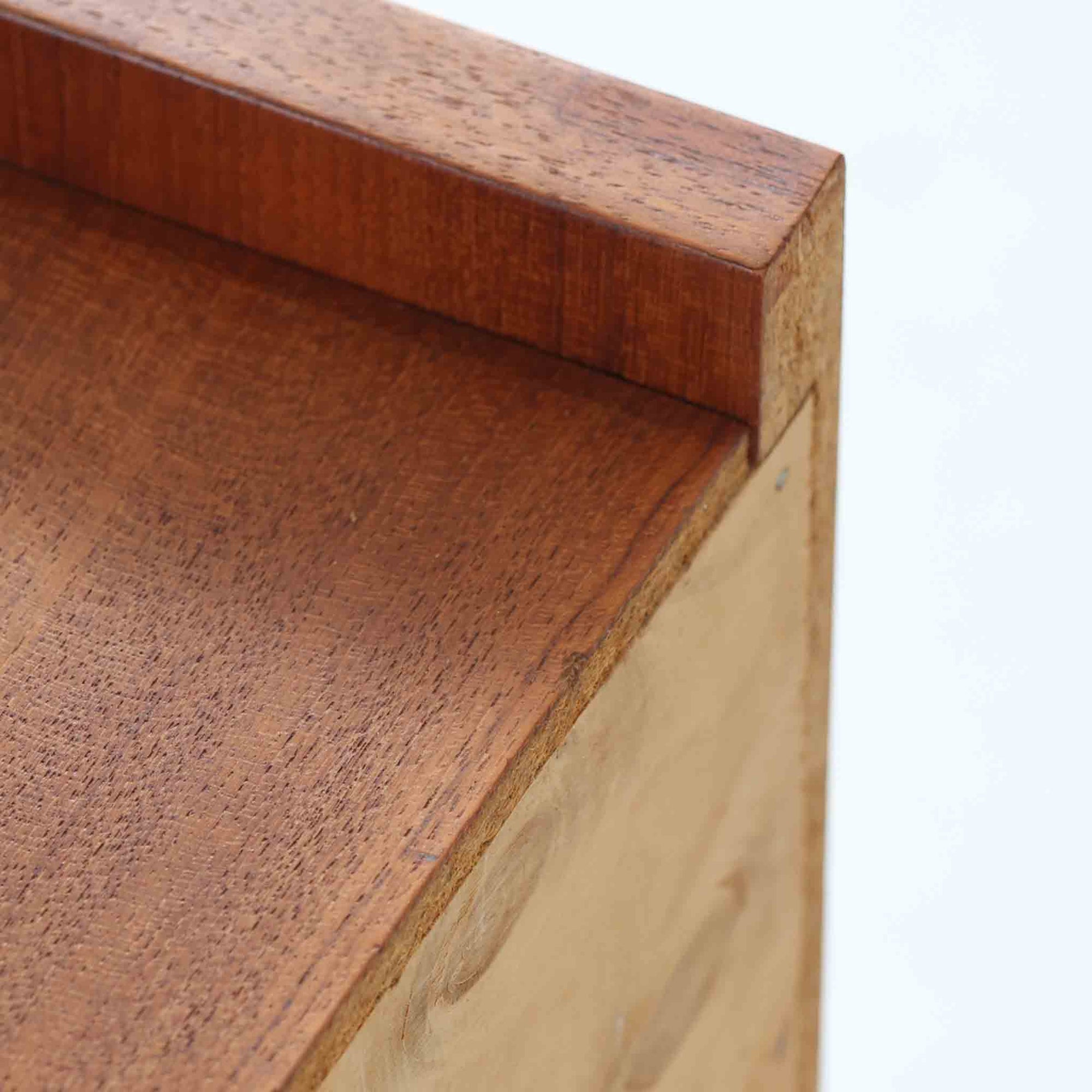 チーク材を用いた小ぶりなキャビネットは、直線を基調としつつ柔らかな丸みを持たせた側板と脚部のラインが印象的な北欧ビンテージ家具です。前板一枚で構成されたフラップ扉には掘り込み式の取っ手が設けられ、開閉時の所作も美しく、内部には実用的な収納棚を備えています。幅69cmと取り入れやすいサイズ感で、リビングや玄関、ベッドサイドの収納としても活躍し、経年により深みを増したチーク材の木目と職人技が静かな存在感を放つ一台です。