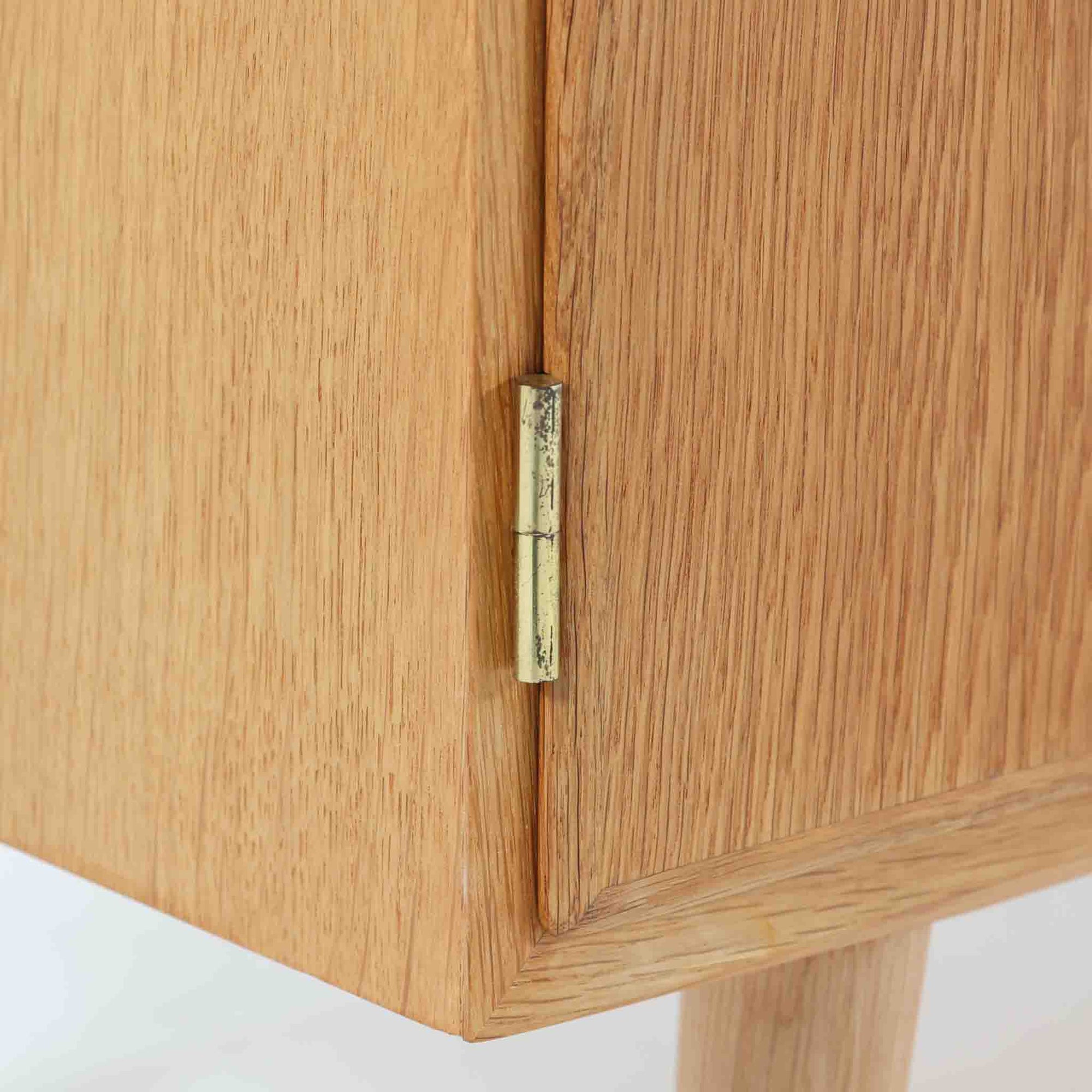 Poul Hundevadが手がけ、Hundevad &amp; Coより製作されたキャビネットです。オーク材の端正な木目を活かしたフラットな扉構成と、細身のテーパードレッグが北欧モダンらしい軽やかさを演出します。内部は可動棚と可動式の浅型トレイを備え、書類や食器、小物まで用途に応じた整理が可能。天板下の構造や金物の収まりにも丁寧な作りが感じられ、長年の使用で深みを増した素材感がビンテージならではの魅力として空間に静かな存在感を添えます。
