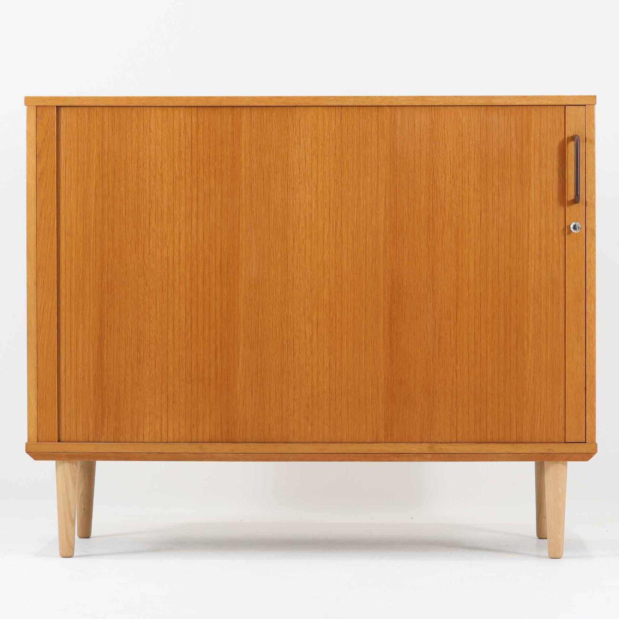 デンマーク製のボードです。温かみのあるオーク材を使用し、滑らかに開閉する蛇腹扉が特徴的な一台。内部は可動棚付きで収納力があり、食器や書類、日用品などをすっきりと収められます。丸みを帯びた脚部が軽やかな印象を与え、幅116cmの程よいサイズ感はリビングやダイニング、書斎にも取り入れやすい設計です。経年により深みを増した木目と丁寧なつくりから、北欧ビンテージならではの質実剛健な魅力が感じられる逸品です。