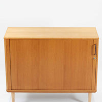 デンマーク製のボードです。温かみのあるオーク材を使用し、滑らかに開閉する蛇腹扉が特徴的な一台。内部は可動棚付きで収納力があり、食器や書類、日用品などをすっきりと収められます。丸みを帯びた脚部が軽やかな印象を与え、幅116cmの程よいサイズ感はリビングやダイニング、書斎にも取り入れやすい設計です。経年により深みを増した木目と丁寧なつくりから、北欧ビンテージならではの質実剛健な魅力が感じられる逸品です。