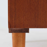 デンマーク製のこちらのローボードは、温かみあるチーク材を用いた端正な佇まいが魅力で、枠組みに厚みをもたせたスライド扉や細身のテーパー脚など、北欧ビンテージらしい上質な意匠が随所に感じられる一台です。内部は左右で棚構成が異なり、日用品から書類、メディア類まで整理しやすく、テレビボードやサイドキャビネットとしても活躍します。経年により深みを増した木肌の美しさと、シンプルながら丁寧に仕上げられた職人技が空間に落ち着きと温もりを添えるビンテージ家具です。