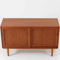 デンマーク製のこちらのローボードは、温かみあるチーク材を用いた端正な佇まいが魅力で、枠組みに厚みをもたせたスライド扉や細身のテーパー脚など、北欧ビンテージらしい上質な意匠が随所に感じられる一台です。内部は左右で棚構成が異なり、日用品から書類、メディア類まで整理しやすく、テレビボードやサイドキャビネットとしても活躍します。経年により深みを増した木肌の美しさと、シンプルながら丁寧に仕上げられた職人技が空間に落ち着きと温もりを添えるビンテージ家具です。