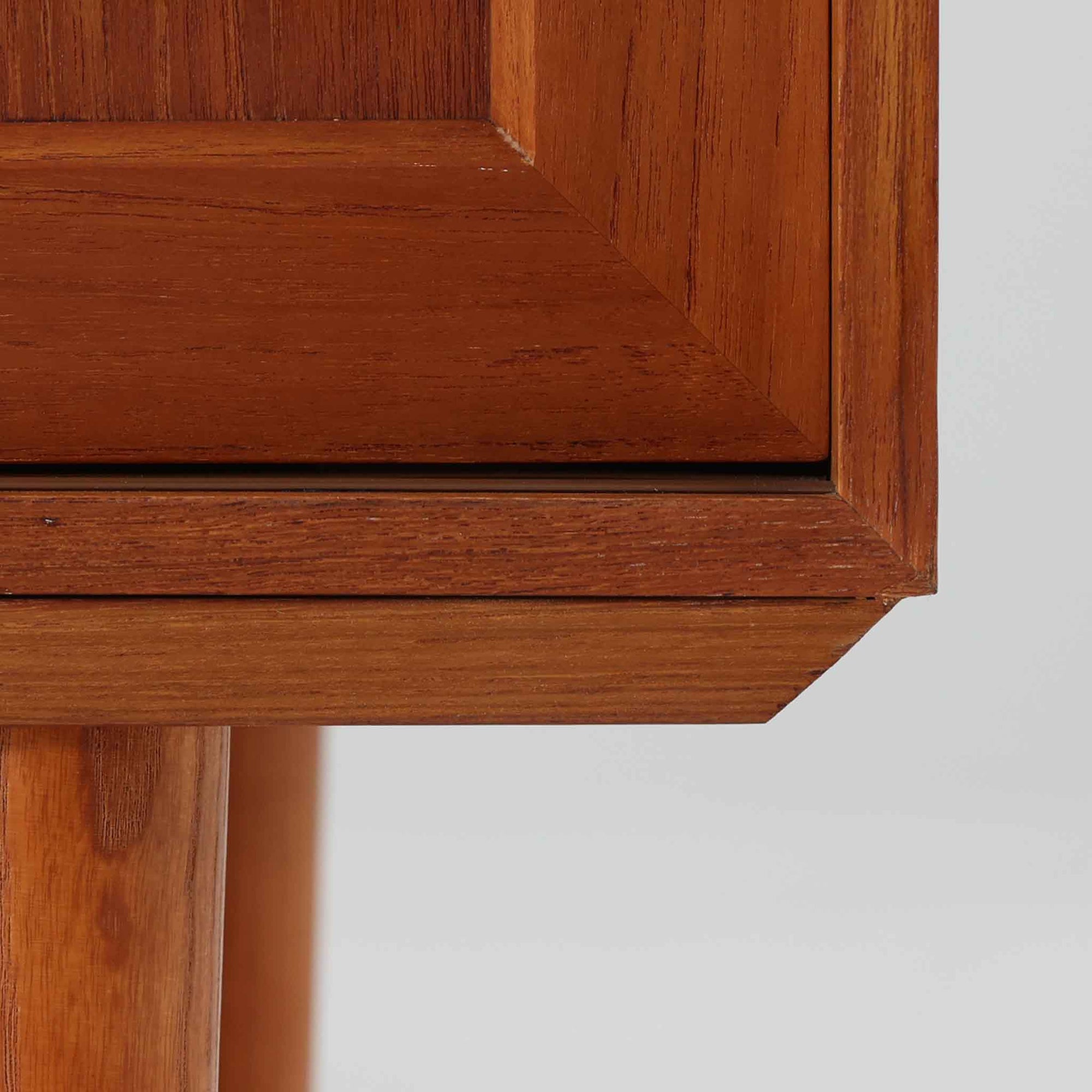 デンマーク製のこちらのローボードは、温かみあるチーク材を用いた端正な佇まいが魅力で、枠組みに厚みをもたせたスライド扉や細身のテーパー脚など、北欧ビンテージらしい上質な意匠が随所に感じられる一台です。内部は左右で棚構成が異なり、日用品から書類、メディア類まで整理しやすく、テレビボードやサイドキャビネットとしても活躍します。経年により深みを増した木肌の美しさと、シンプルながら丁寧に仕上げられた職人技が空間に落ち着きと温もりを添えるビンテージ家具です。