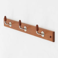 チーク材の温かみあるベースにメタル製の3連フックを組み合わせたデンマーク製のウォールハンガーです。丸みのある木製キャップ付きのフックはコートやバッグを掛けても傷つきにくく、機能性とデザイン性を両立した北欧ビンテージらしいディテールが魅力です。玄関や寝室、ワークスペースなど壁面を活用した収納に便利で、単体での使用はもちろん複数並べて使用しても美しく空間に溶け込みます。ミニマルなデザインでインテリアを選ばず永くお使いいただけるアイテムです。