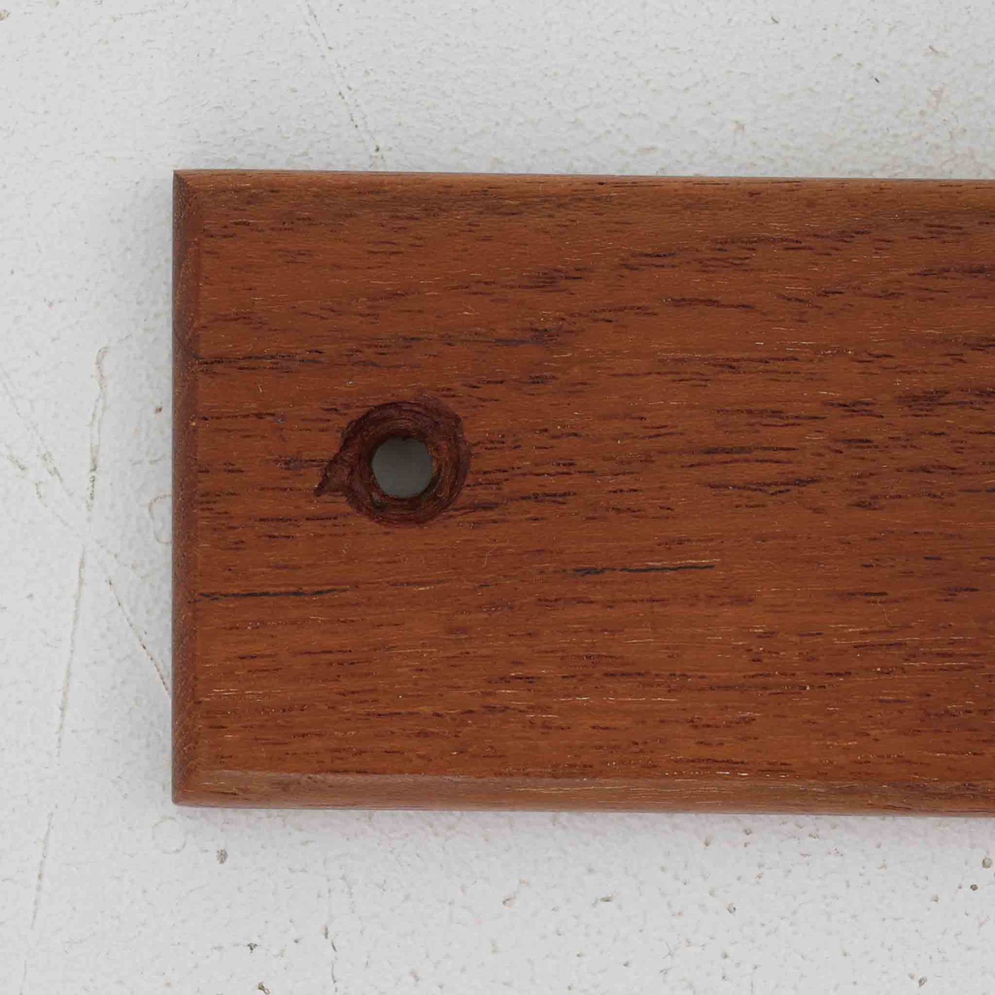 チーク材の温かみあるベースにメタル製の3連フックを組み合わせたデンマーク製のウォールハンガーです。丸みのある木製キャップ付きのフックはコートやバッグを掛けても傷つきにくく、機能性とデザイン性を両立した北欧ビンテージらしいディテールが魅力です。玄関や寝室、ワークスペースなど壁面を活用した収納に便利で、単体での使用はもちろん複数並べて使用しても美しく空間に溶け込みます。ミニマルなデザインでインテリアを選ばず永くお使いいただけるアイテムです。