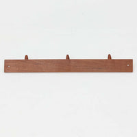 チーク材の温かみあるベースにメタル製の3連フックを組み合わせたデンマーク製のウォールハンガーです。丸みのある木製キャップ付きのフックはコートやバッグを掛けても傷つきにくく、機能性とデザイン性を両立した北欧ビンテージらしいディテールが魅力です。玄関や寝室、ワークスペースなど壁面を活用した収納に便利で、単体での使用はもちろん複数並べて使用しても美しく空間に溶け込みます。ミニマルなデザインでインテリアを選ばず永くお使いいただけるアイテムです。