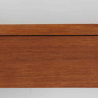 チーク材を用いたこちらのウォールシェルフは、直線的な棚板に両端の立ち上がりを設けた端正なフォルムが印象的な北欧ビンテージ家具です。前面には掘り込み式の取っ手を備えた引き出しが組み込まれており、見た目の軽やかさを保ちながら、実用的な収納力も確保しています。壁面を有効活用できる構造のため、デスク上やベッドサイド、玄関周りの小物収納としても取り入れやすく、側板は縁に向かって面取りが施され、厚みの変化によって立体感と柔らかな印象を与えています。経年により深みを増したチーク材の木目と丁寧な作りが、空間に静かな存在感を添える一台です。