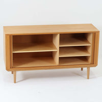 Poul Hundevadがデザインし、Hundevad & Coより製作された蛇腹仕様のサイドボードです。オーク材の穏やかで上品な木目を活かした外観に、横方向へ滑らかに開閉する蛇腹扉を組み合わせた、機能美あふれる一台。扉の開閉時に前後のスペースを取らない構造は、動線を妨げず実用性にも優れています。内部は棚板構成で収納力が高く、食器や書類、リビング周りの小物まで幅広く対応。細身の脚部が全体を軽やかに引き締め、経年によって深みを増した素材感が北欧ビンテージならではの静かな存在感を空間にもたらします。