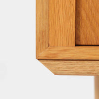 Poul Hundevadがデザインし、Hundevad & Coより製作された蛇腹仕様のサイドボードです。オーク材の穏やかで上品な木目を活かした外観に、横方向へ滑らかに開閉する蛇腹扉を組み合わせた、機能美あふれる一台。扉の開閉時に前後のスペースを取らない構造は、動線を妨げず実用性にも優れています。内部は棚板構成で収納力が高く、食器や書類、リビング周りの小物まで幅広く対応。細身の脚部が全体を軽やかに引き締め、経年によって深みを増した素材感が北欧ビンテージならではの静かな存在感を空間にもたらします。